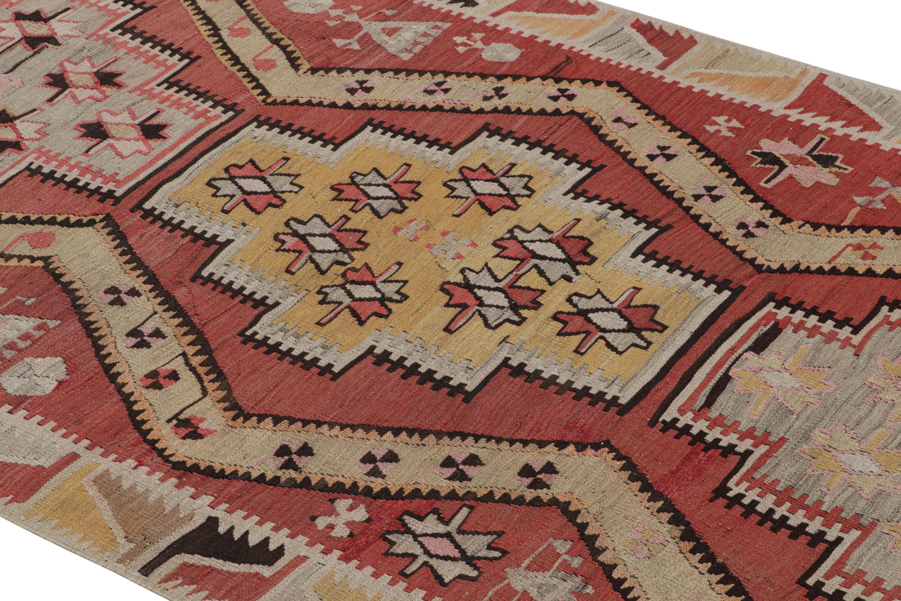 Flat-woven in high-quality wool originating from Turkey between 1930-1940, this vintage Kayseri Kilim rug enjoys inviting floral and subtle tribal imagery throughout the expansive field design, further highlighted by the mirroring of pastel red,