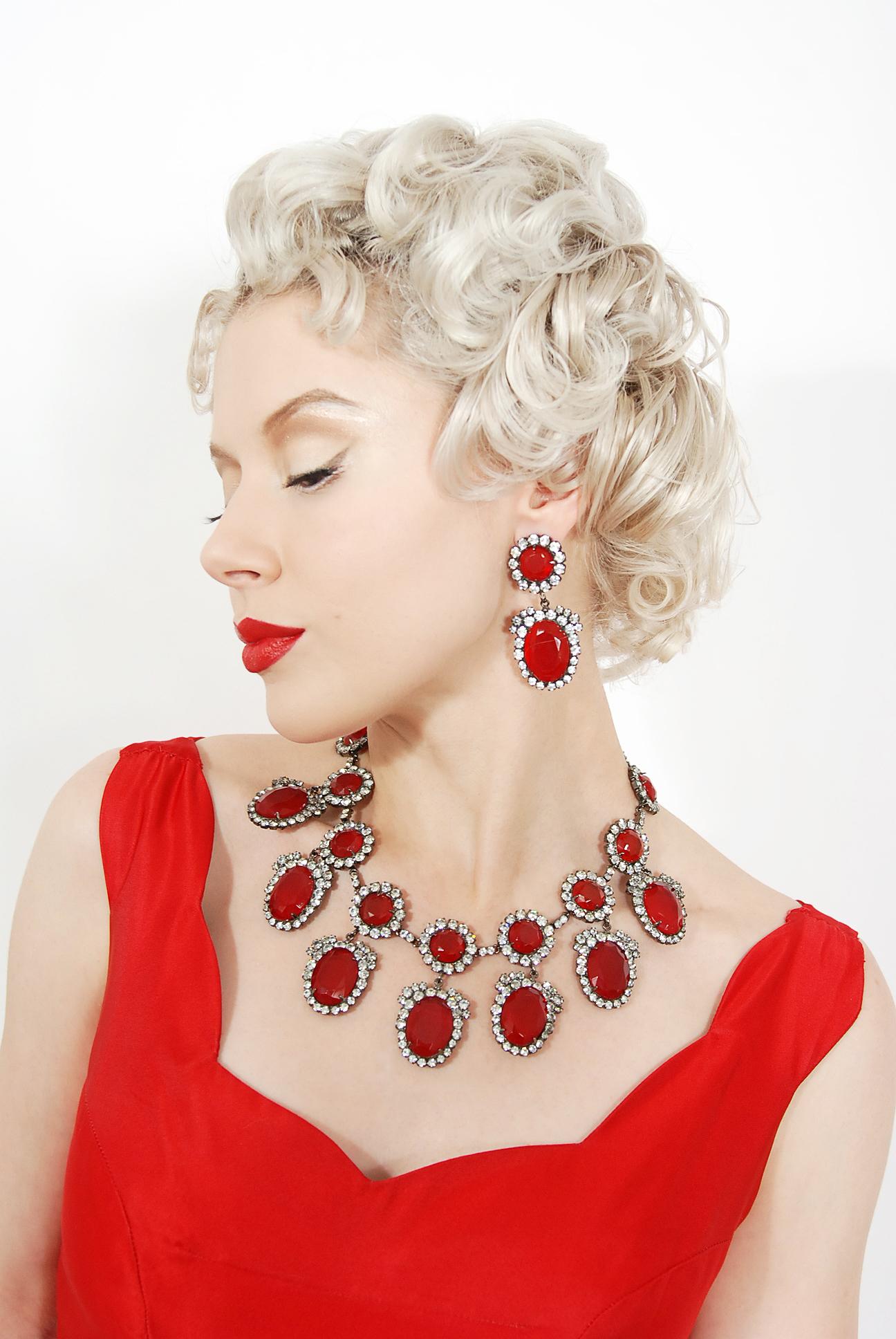 This gorgeous and iconic ruby red necklace with matching drop-earrings was designed by the famous Kenneth Jay Lane. The same version was made for the Duchess of Windsor in 1965 and is shown on page 147 of the 