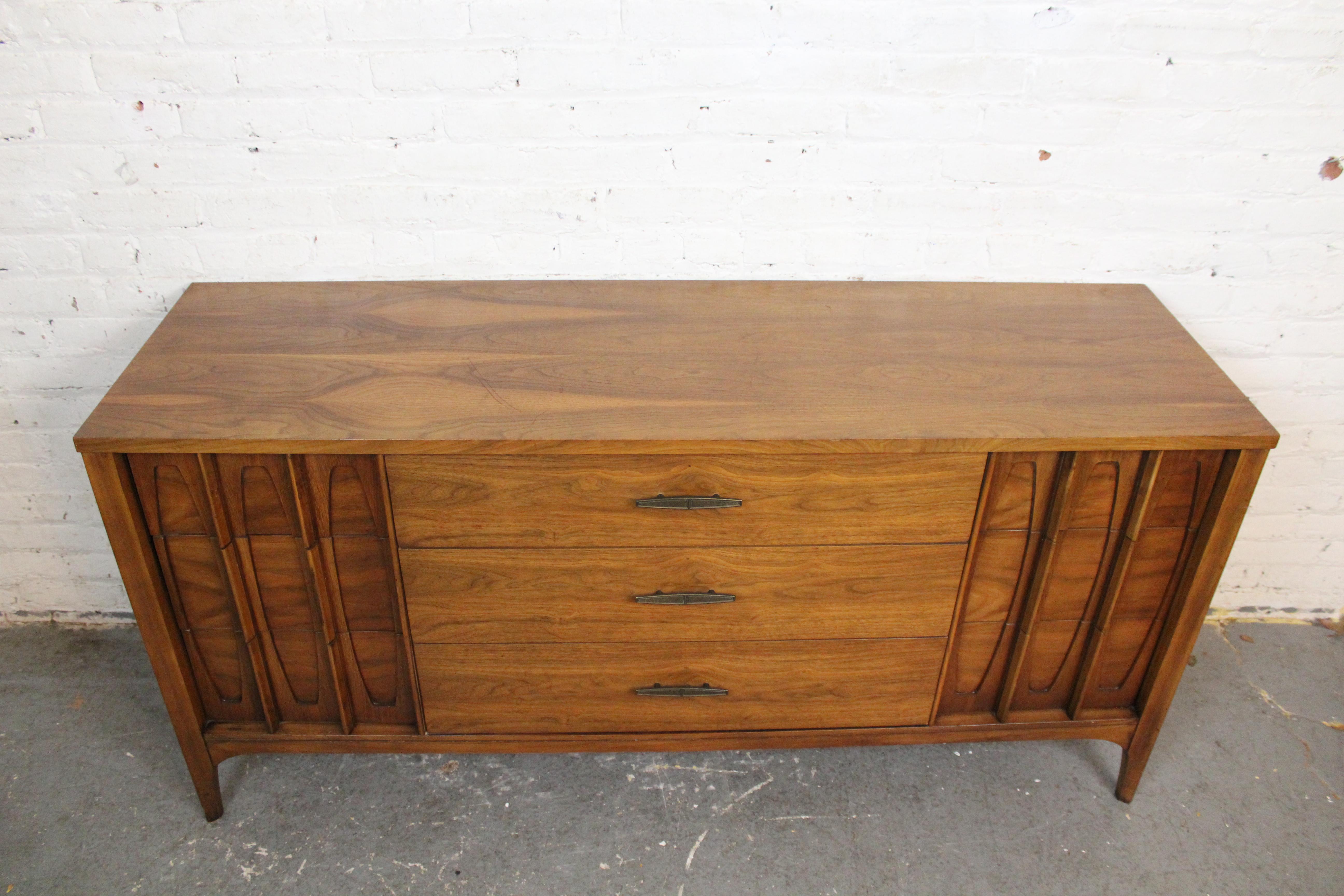 Bring home a classic example of genuine American Mid-Century Modern design with this attractive lowboy dresser by the estimable Kent-Coffey company of North Carolina. With a convenient 9-drawer layout, it features three extra wide pull-out drawers