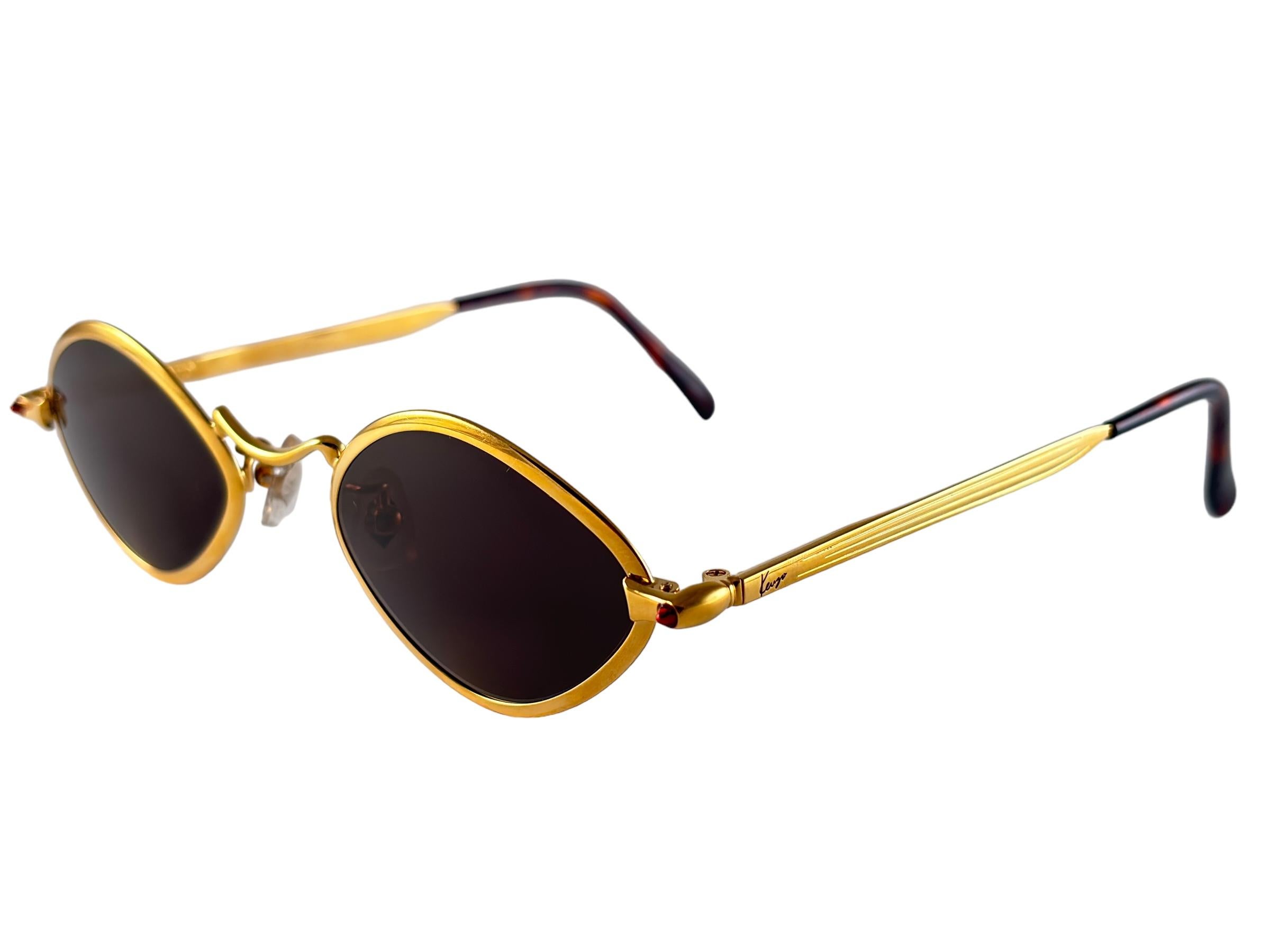 Belle paire de lunettes de soleil Kenzo en forme de petits diamants dorés avec des verres gris unis.
Cette paire présente des signes mineurs d'usure dus au stockage.

Fabriqué au Japon.

Front : 13  cms
Hauteur de l'objectif : 3.6 cm
Largeur de