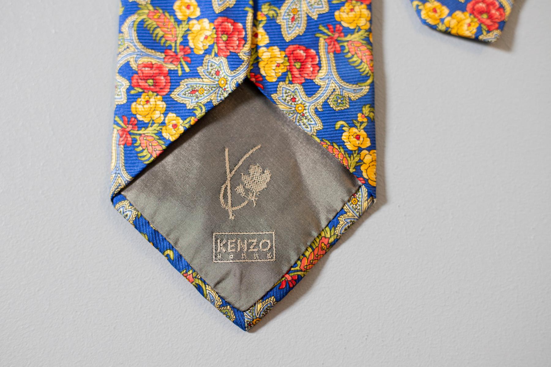 Diese Vintage-Krawatte wurde von Kenzo für seine Kollektion Kenzo Homme entworfen. Diese Krawatte aus reiner Seide ist farbenfroh: Sie zeigt bunte Blumen auf blauem Grund. Einzigartig und originell, perfekt für einen eleganten Anlass.