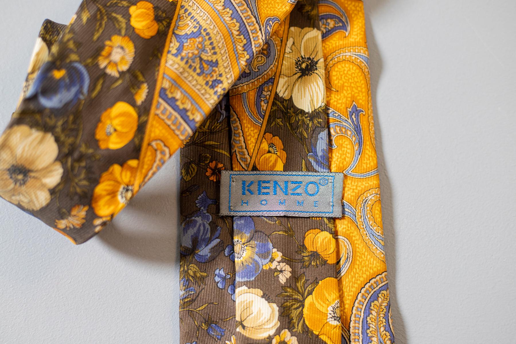 This vintage all-silk tie designed by Kenzo for his collection Kenzo Homme is simply gorgeous. Split in two parts, a yellow one decorated with a paisley motif and a darker one decorated with colourful flowers: this tie is perfect for everyone who