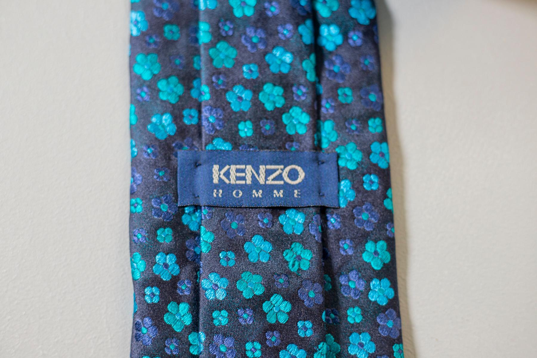 Cette cravate vintage est dans le style classique de Kenzo. Réalisée en toute soie pour la collection Kenzo Homme, cette cravate est décorée de petites fleurs bleues et bleues claires sur un fond bleu foncé. Cet accessoire est parfait pour un