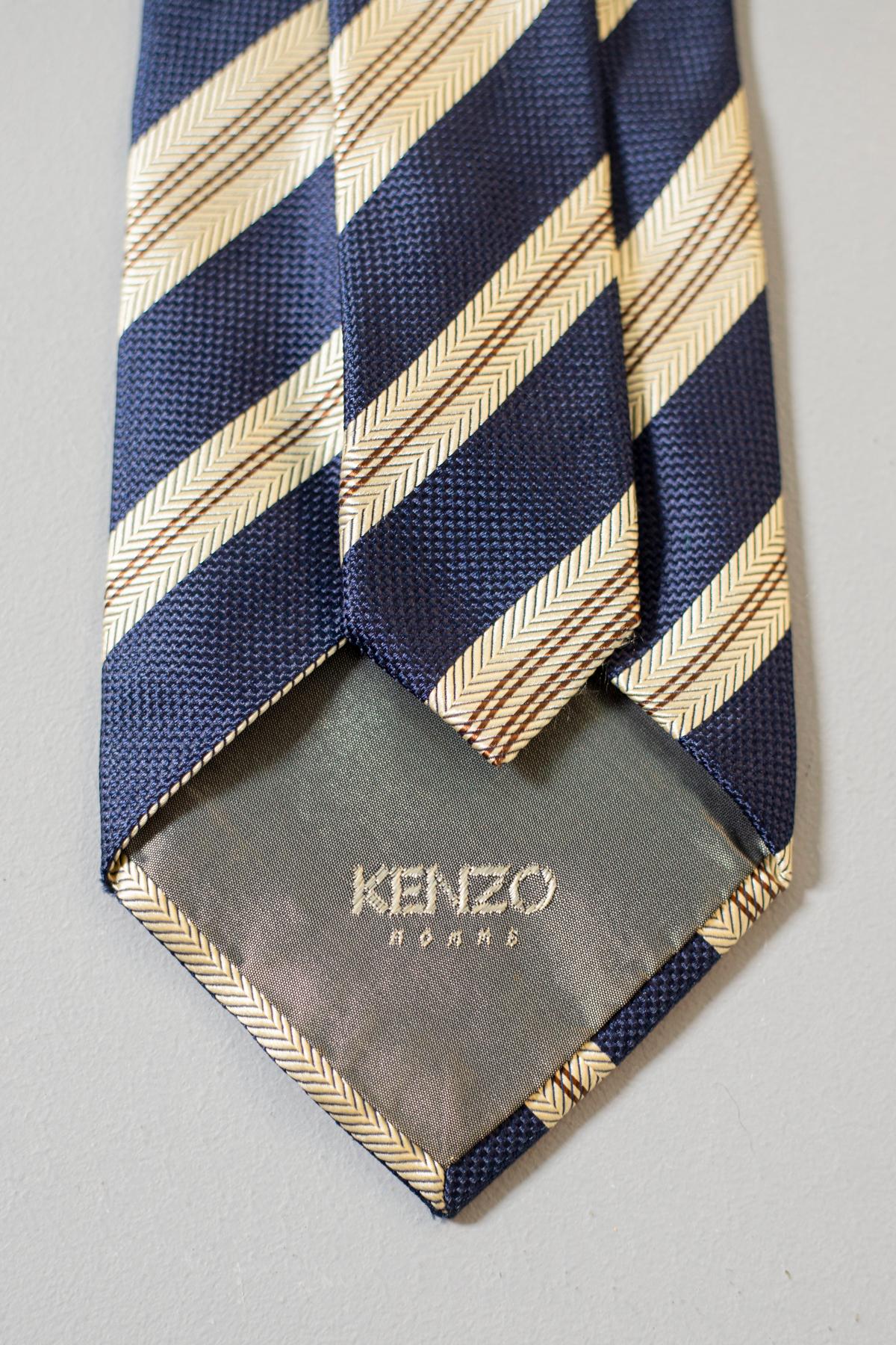 This Kenzo vintage tie is an evergreen. Made in France and designed for Kenzo Homme collection, this tie is a must-have. Decorated with white and beige stripes on a blue background, this accessory is perfect for every formal and informal occasion.