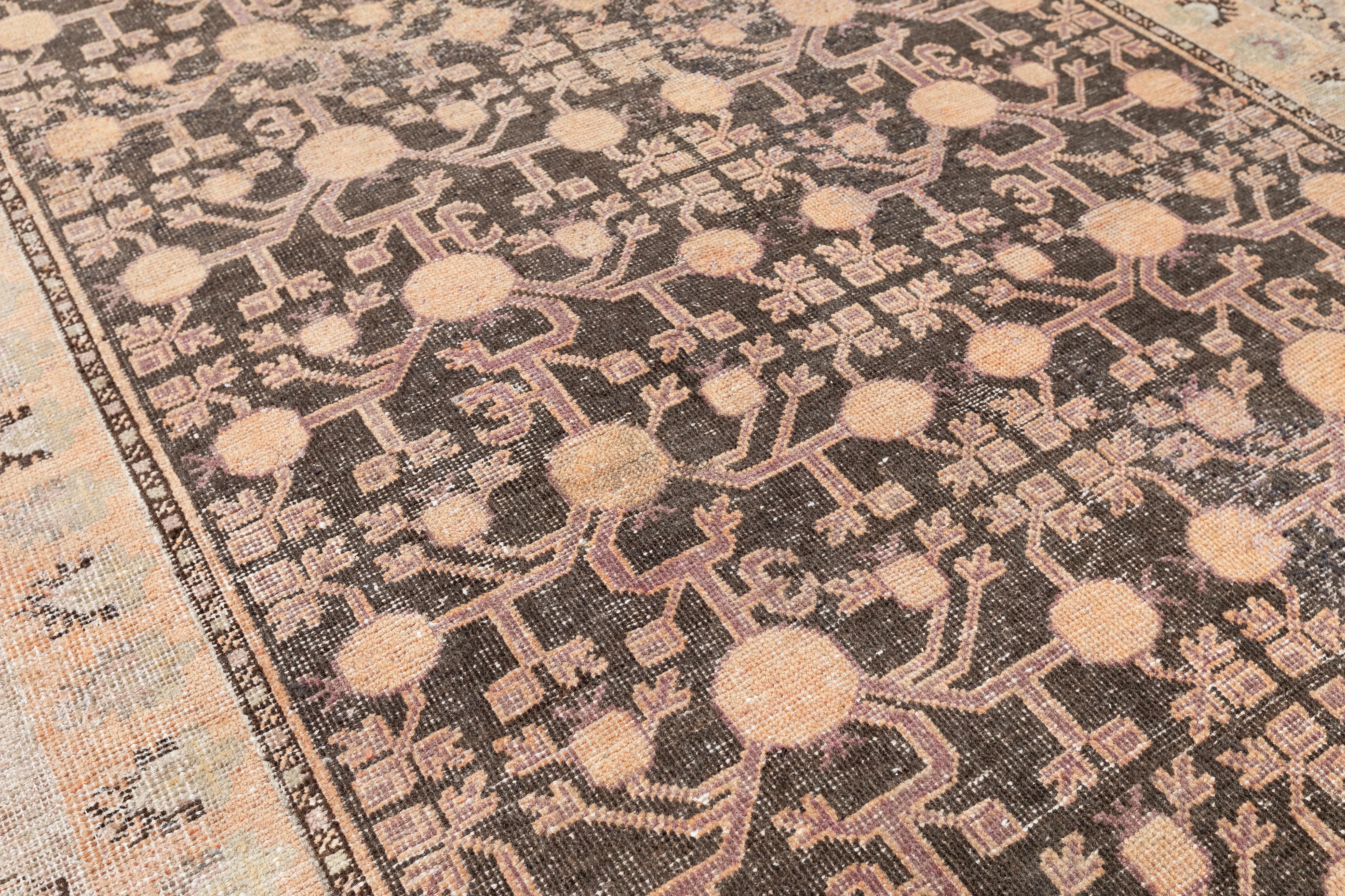 Ce tapis Khotan vintage, tissé en Ouzbékistan il y a environ 70-80 ans, illustre l'art intemporel de l'artisanat d'Asie centrale. Tissé à la main à partir de laine teintée avec des pigments végétaux biologiques, les tons marron et blush délavés du