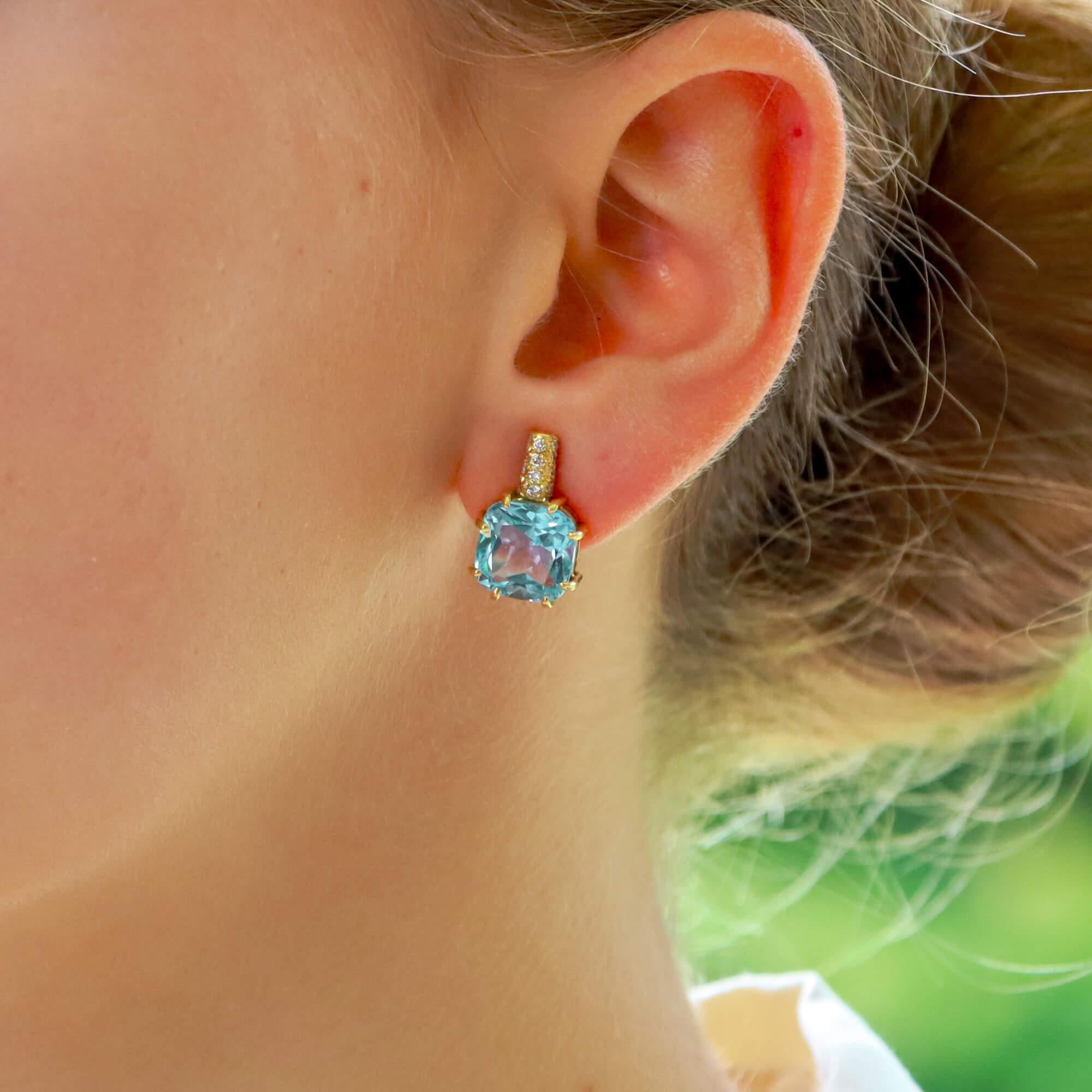 A beautiful vintage pair of Kiki McDonough blue topaz and diamond earrings set in 18k yellow gold.

Each earring is predominantly set with a gorgeous sky-blue coloured cushion cut blue topaz stone, eight claw set securely. To the top is a soldered