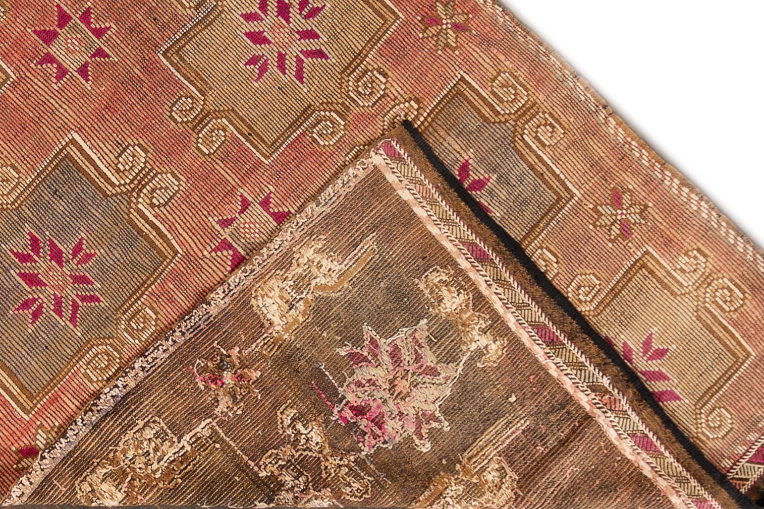 A hand knotted vintage Kilim flat-weave rug with a salmon field and an all-over geometric design. This rug measures 5'5