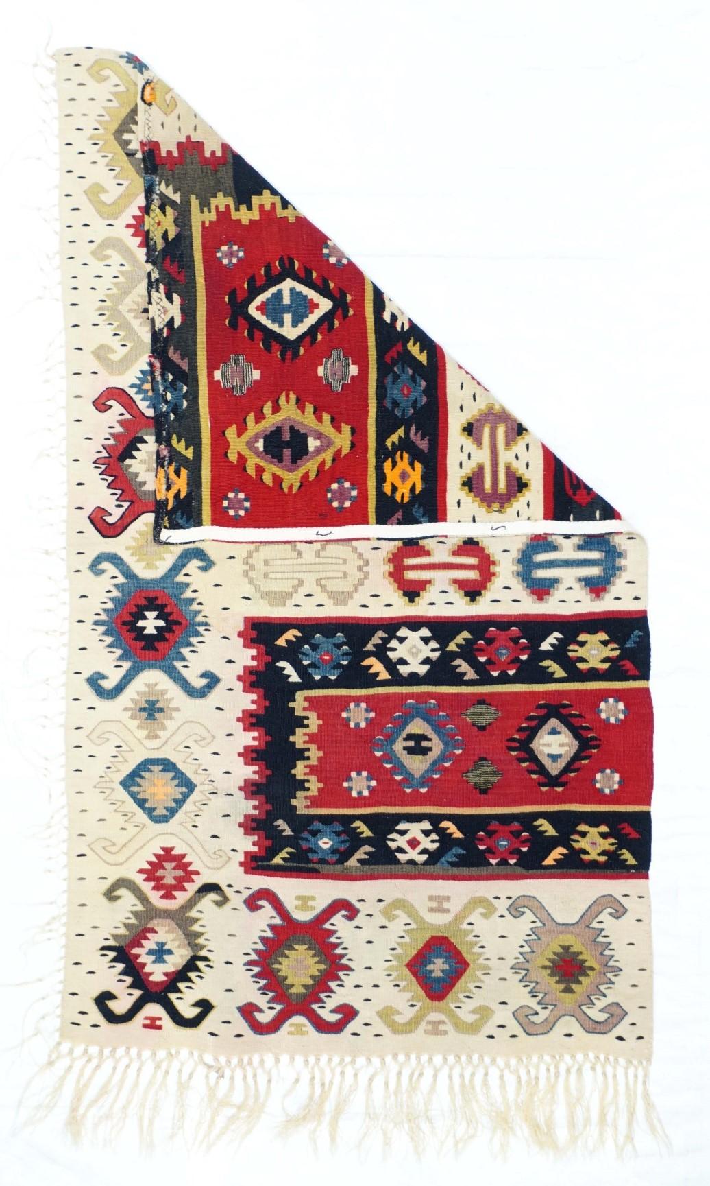 Vintage Kilim rug 2'3'' x 4'2''. Similar to our 1928 and 1944, this attractive fragment shows two partial red panels with ashiks, within black borders, and set on an overall cream ground with a double hook ashik border. Would make a great cushion.