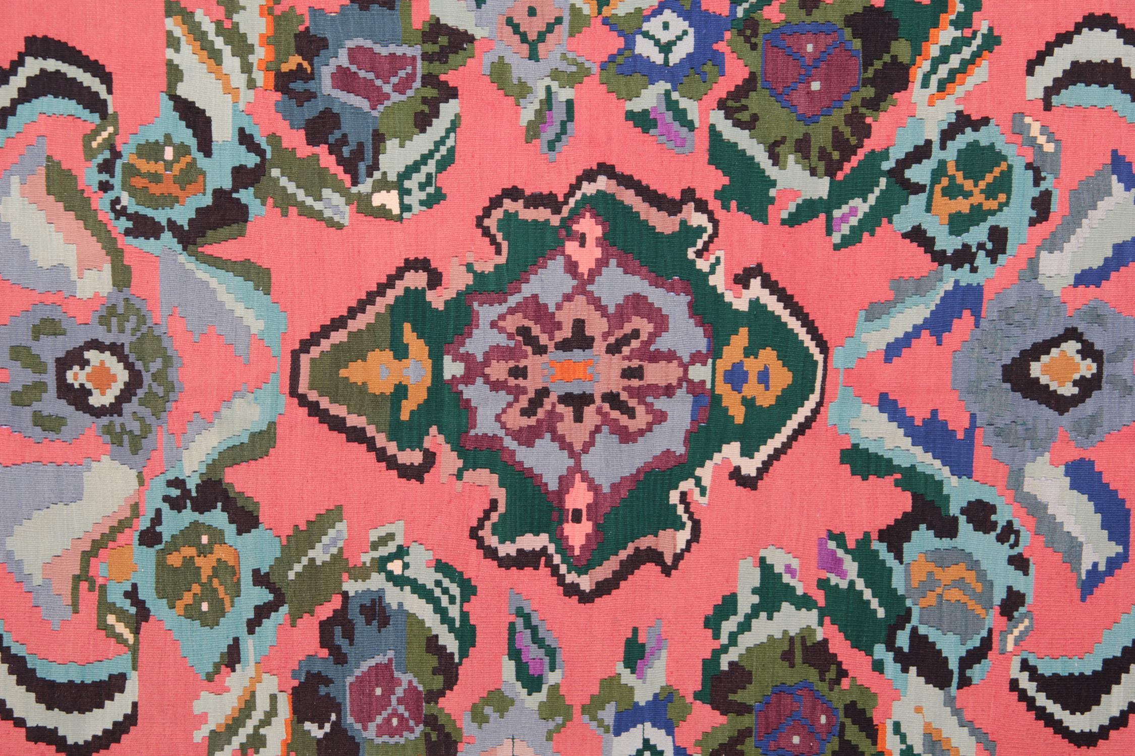 This handmade carpet colorful Turkish carpet rug is woven by very skilled weavers in Turkey, who used the highest quality wool and cotton. The flat-weave rug has light blue, orange Salmon, green, white, pink, black and brown colours. The pink rug