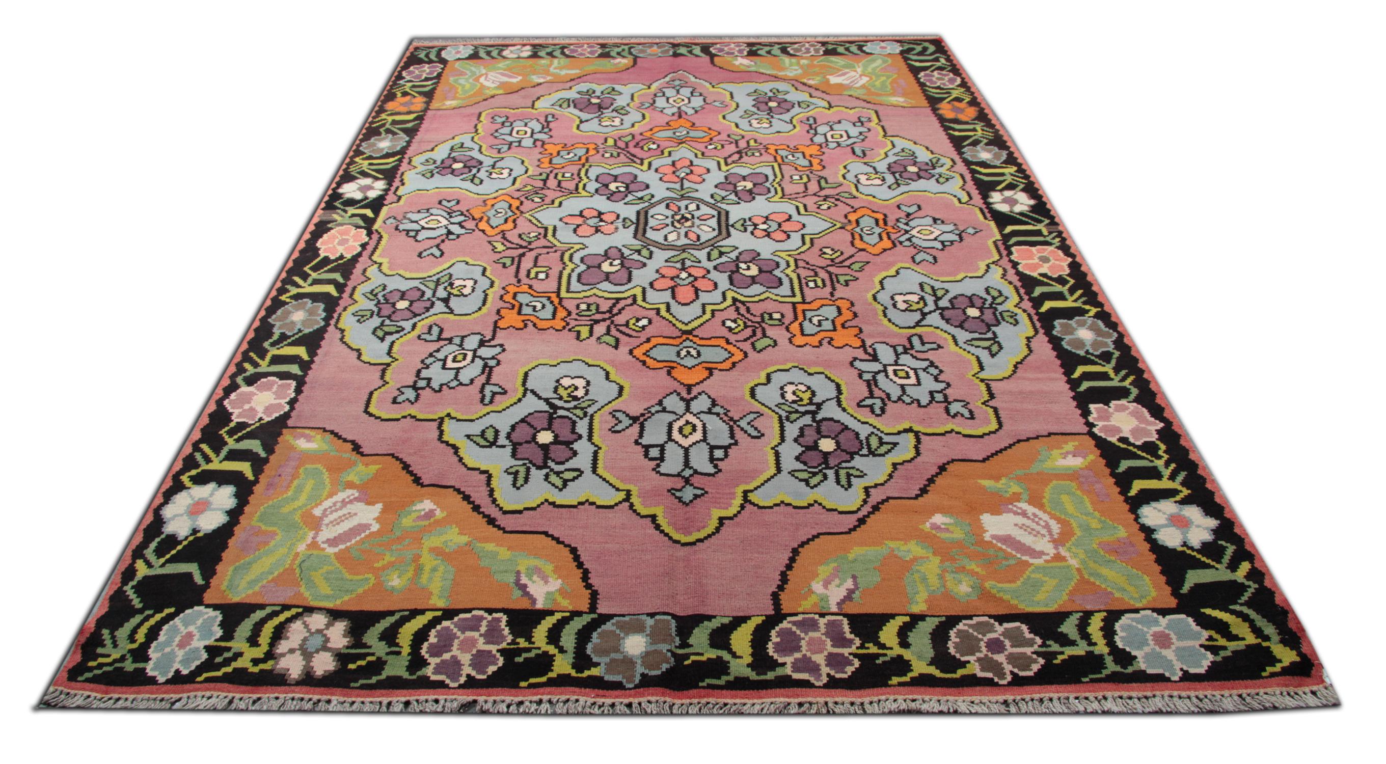 This handmade carpet colourful Turkish rug is woven by very skilled weavers in Turkey, who used the highest quality wool and cotton. The flat-weave rug has light blue, orange, green, white, pink and brown colours. The pink background of this floral