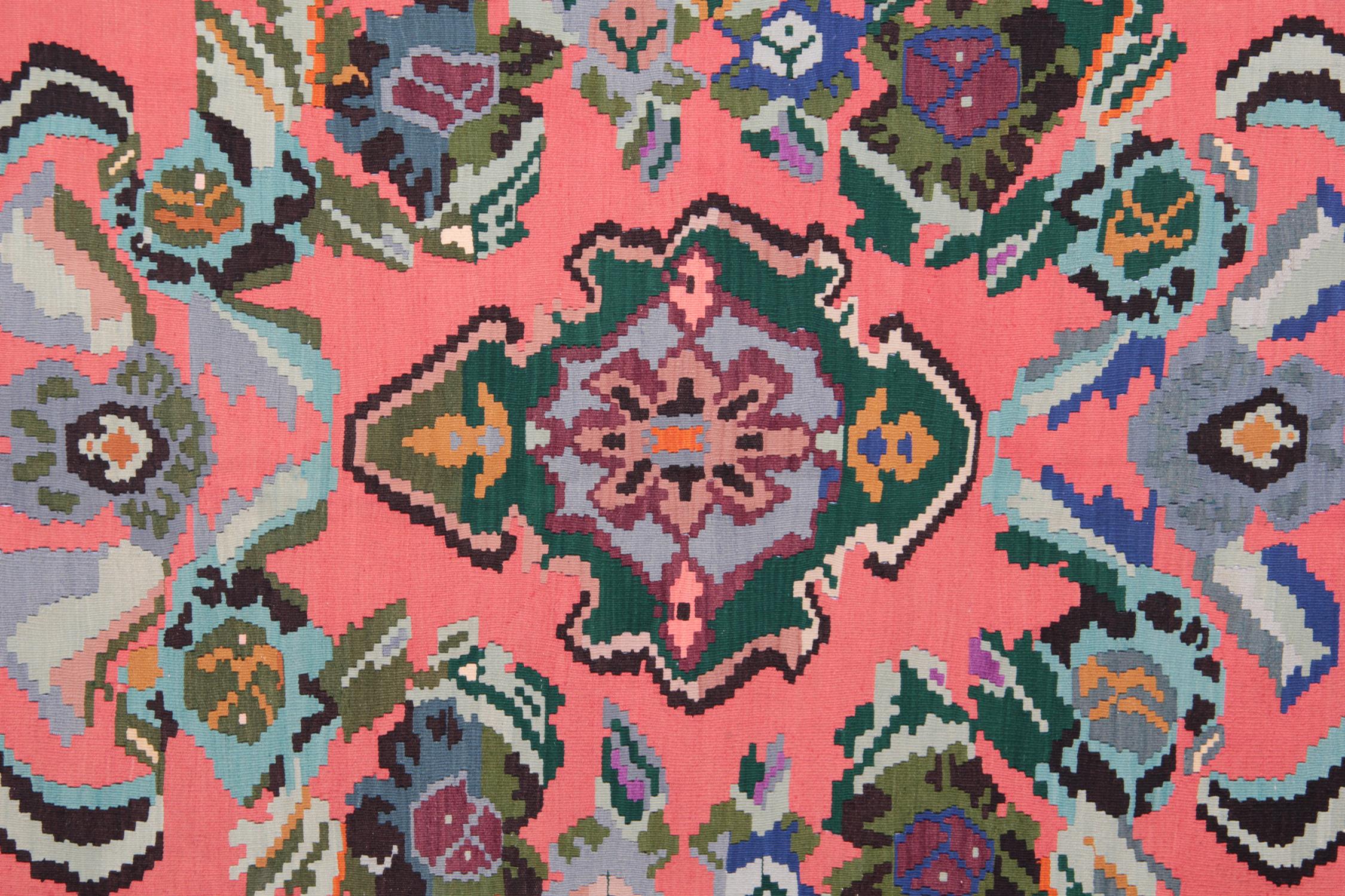 Esta colorida alfombra turca hecha a mano está tejida por tejedores muy hábiles de Turquía, que utilizan lana y algodón de la mejor calidad. La alfombra de tejido plano tiene colores azul claro, naranja salmón, verde, blanco, rosa, negro y marrón.