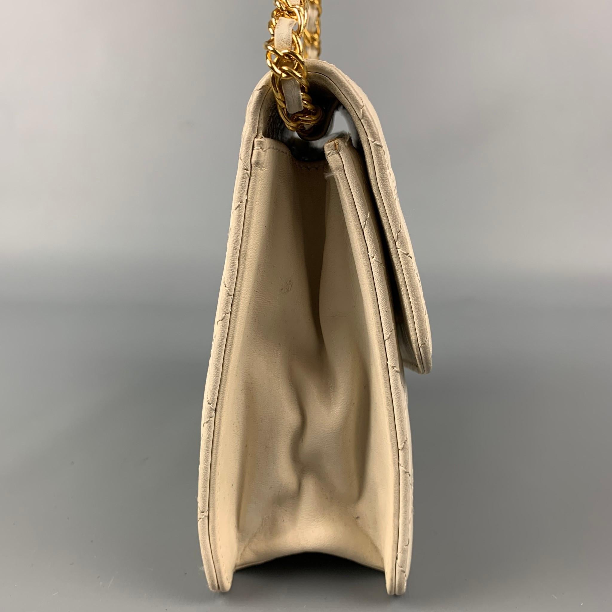 Vintage KIMIJIMA handbag comes in a cream quilted leather featuring a front gold tone bow detail, chain shoulder strap, inner pocket, and a snap button closure. 

Good Pre-Owned Condition.

Measurements:

Length: 5.75 in.
Width: 2.25 in.
Height: 6.5