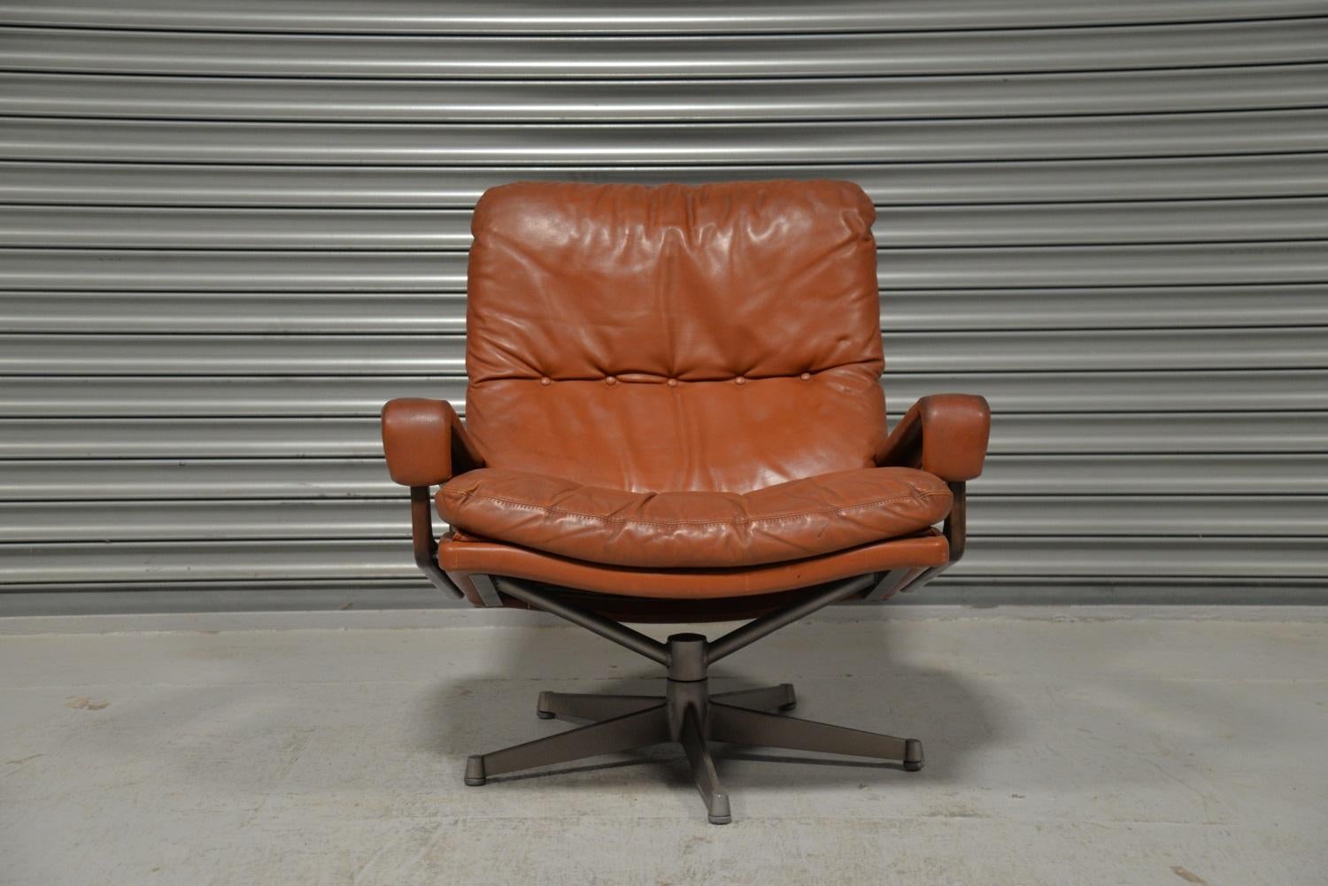 A vintage lounge King armchair by Strassle of Switzerland. Designed by Andre Vandenbeuck of Belgium, the swivel lounge armchair is upholstered in stunning tan leather. Hand built in Switzerland to incredibly high standards, the armchair has rosewood