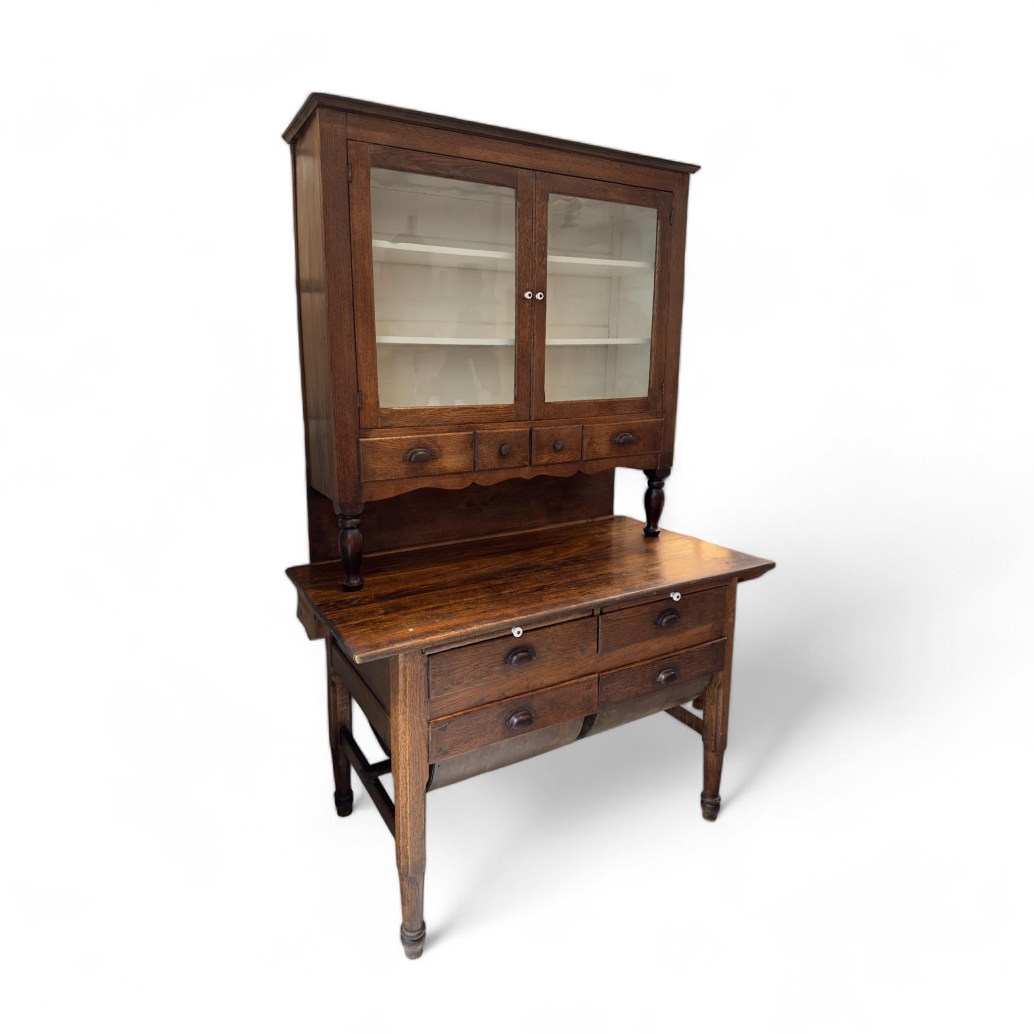 Dieser Vintage-Küchenschrank versprüht rustikalen Charme und klassische Anziehungskraft und ist damit eine perfekte Ergänzung für jede Küche oder jeden Essbereich im Landhausstil. Der aus dunklem Holz gefertigte Schrank verfügt über eine Glasfront,