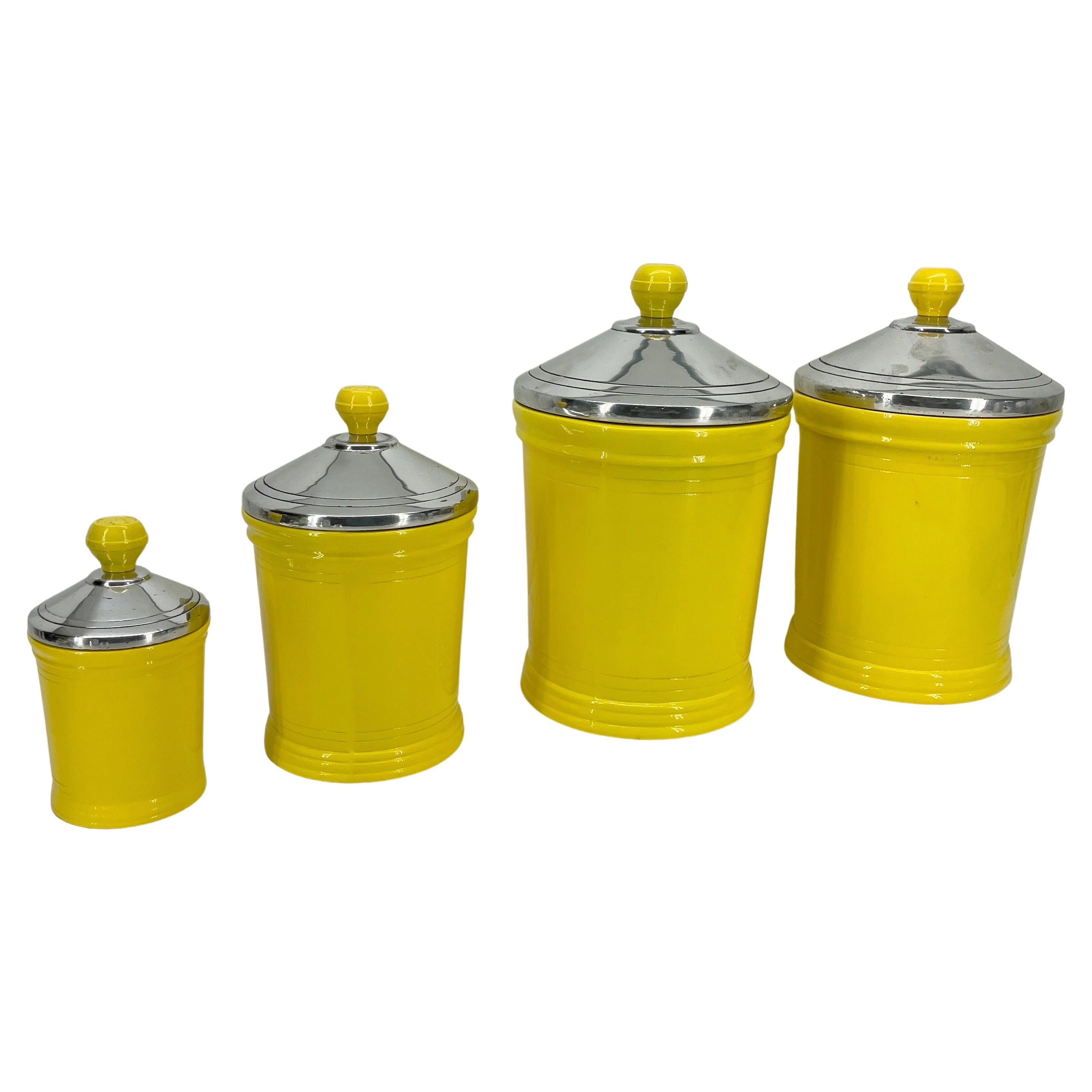 Mid-Century Modern four-piece set of bright sunshine yellow kitchen canister jars, circa 1960's. The charming and bold jars are complete with their original polished chrome lids. Once a staple in every kitchen, the newly powder coated canisters
