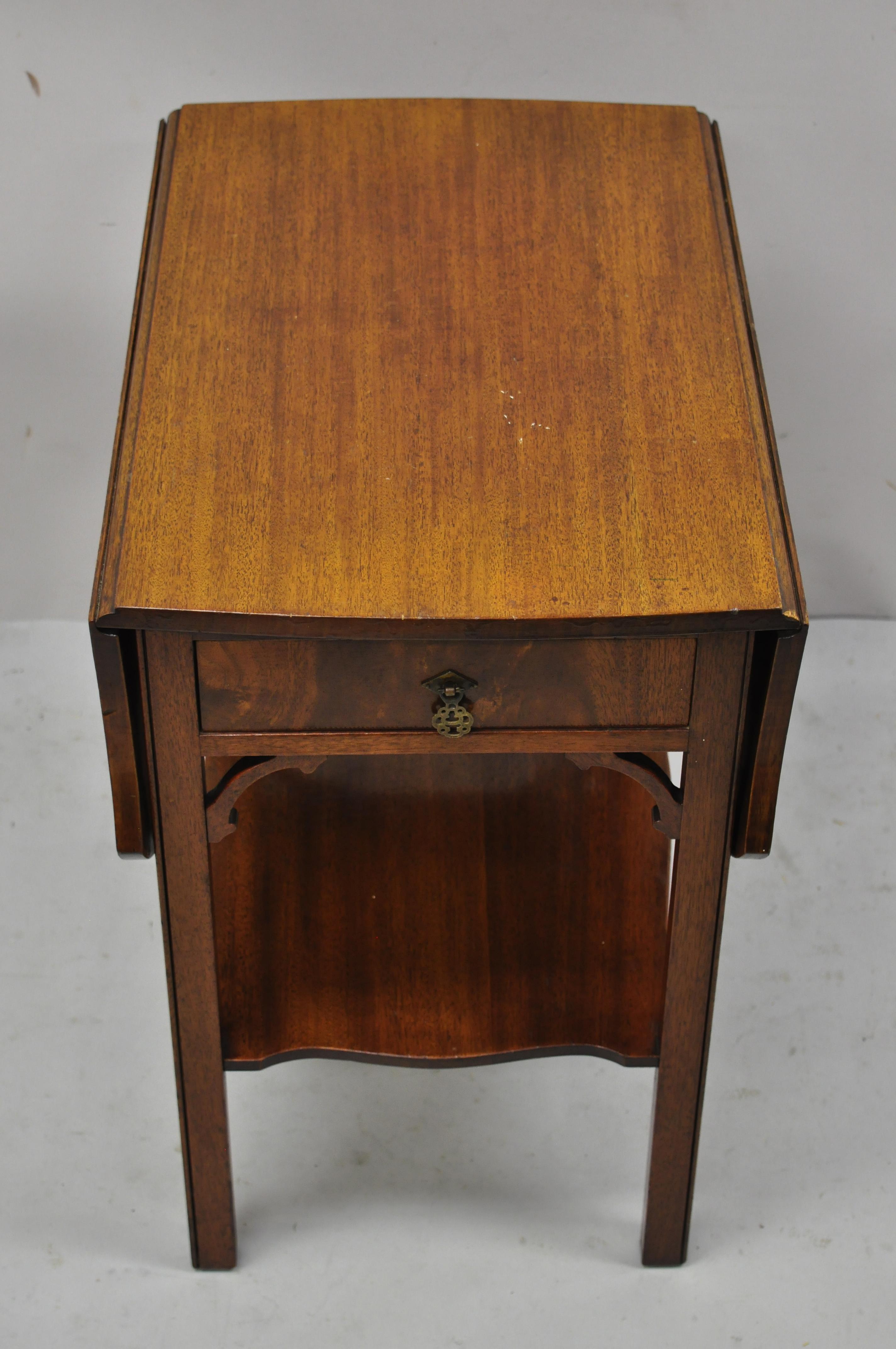 Vintage Kittinger buffalo mahogany Chippendale drop leaf side end lamp table. Item features lower shelf, fretwork carving, dropleaf sides, beautiful wood grain, finished back, original label, 1 dovetailed drawers, quality American craftsmanship,
