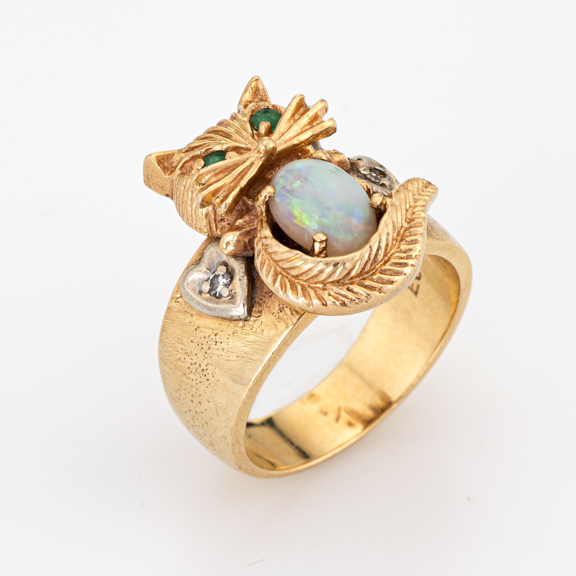 Stylish vintage kitty cat ring (circa 1960s to 1970s) crafted in 14 karat yellow gold. 

Cabochon cut opal is estimated at 0.50 carats, accented with two estimated 0.02 carat emeralds and two approx. 0.01 carat single cut diamonds. The opal is in