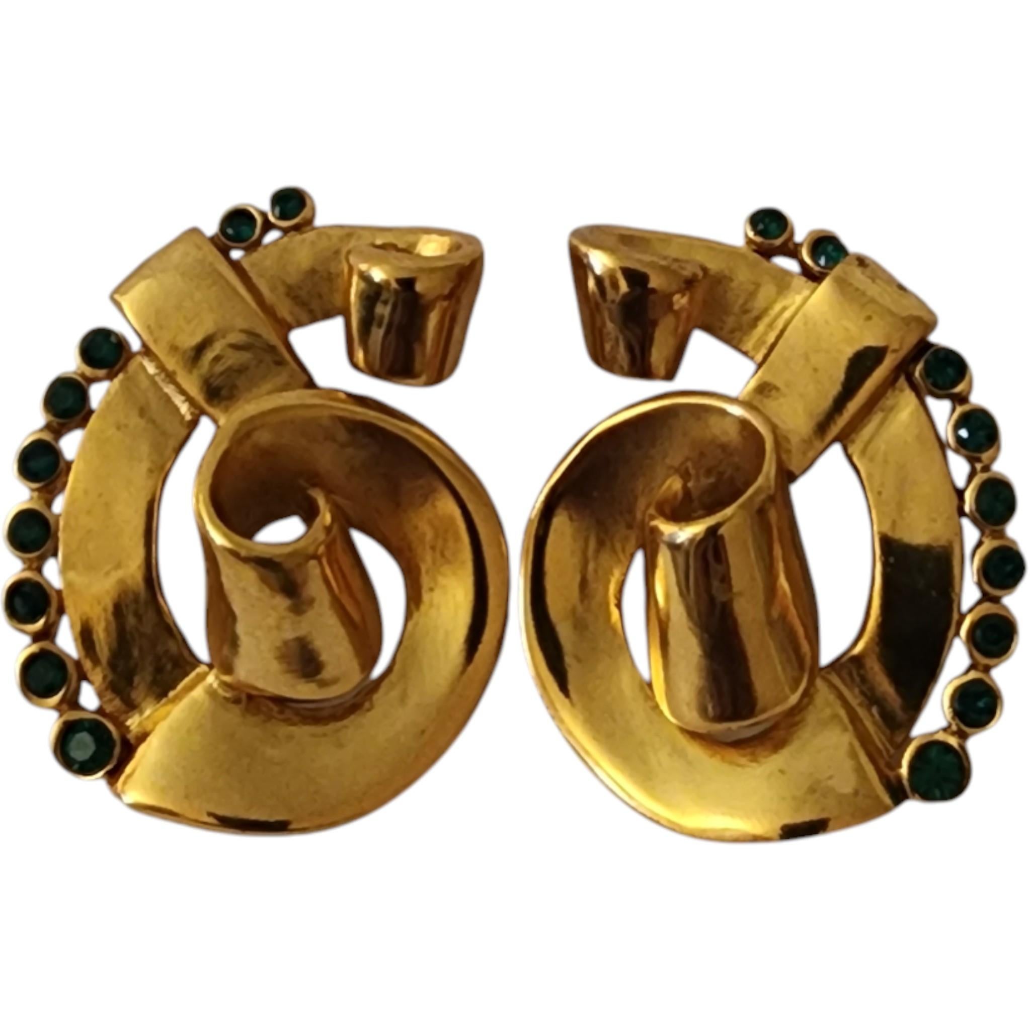 Setzen Sie ein Zeichen mit diesen glamourösen Vintage-Ohrringen von Kenneth Jay Lane (KJL). Diese auffälligen Clip-Ons aus goldfarbenem Metall haben ein elegantes, skulpturales Wirbeldesign, das mit einer Reihe smaragdgrüner Strasssteine akzentuiert
