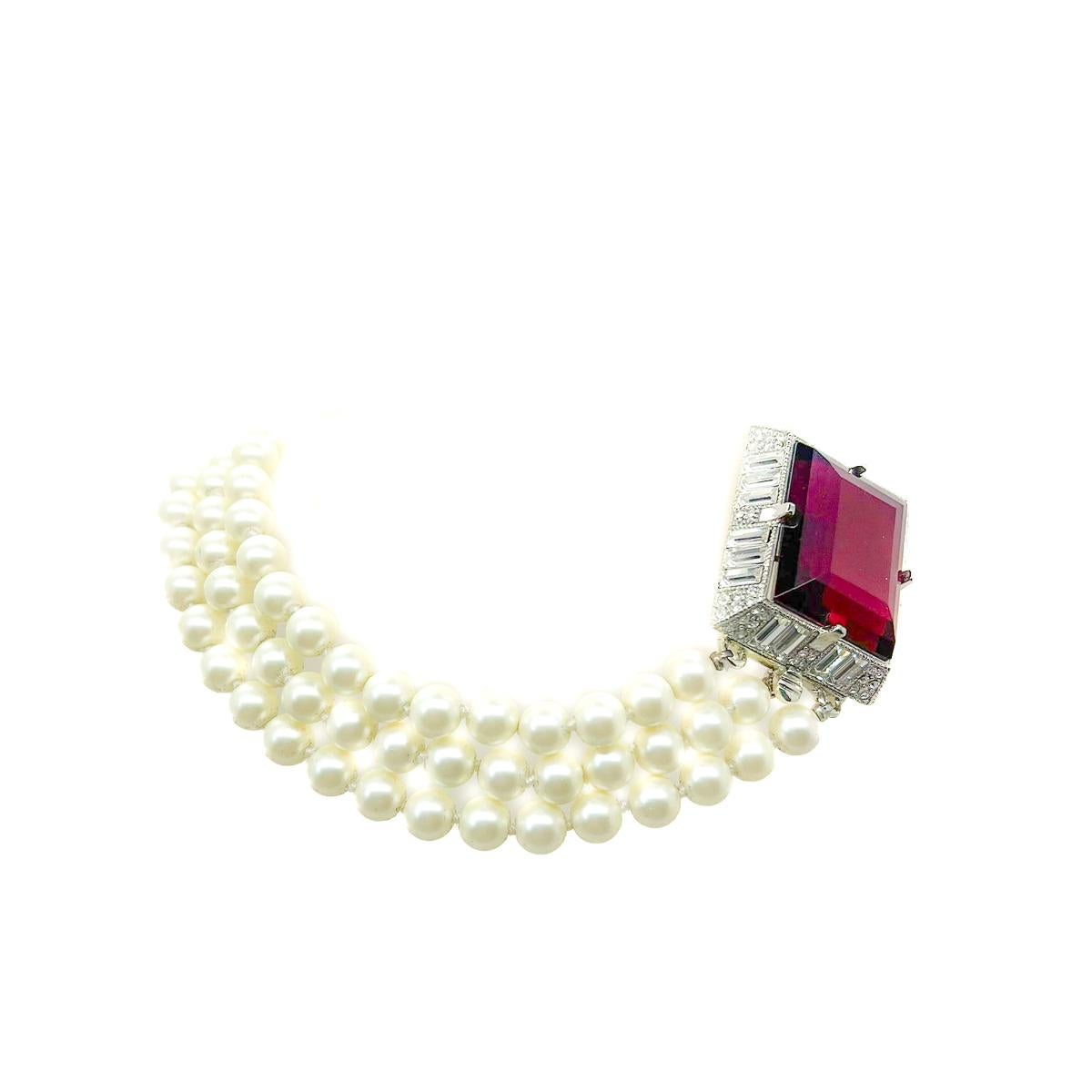 Une fabuleuse torsade vintage de Kenneth Lane en rubis et perles. Un énorme cristal rouge rubis est monté sur une haute monture ornée de cristaux baguette et de cristaux chaton, ce qui lui confère une allure Art déco. Des rangées de perles lustrées