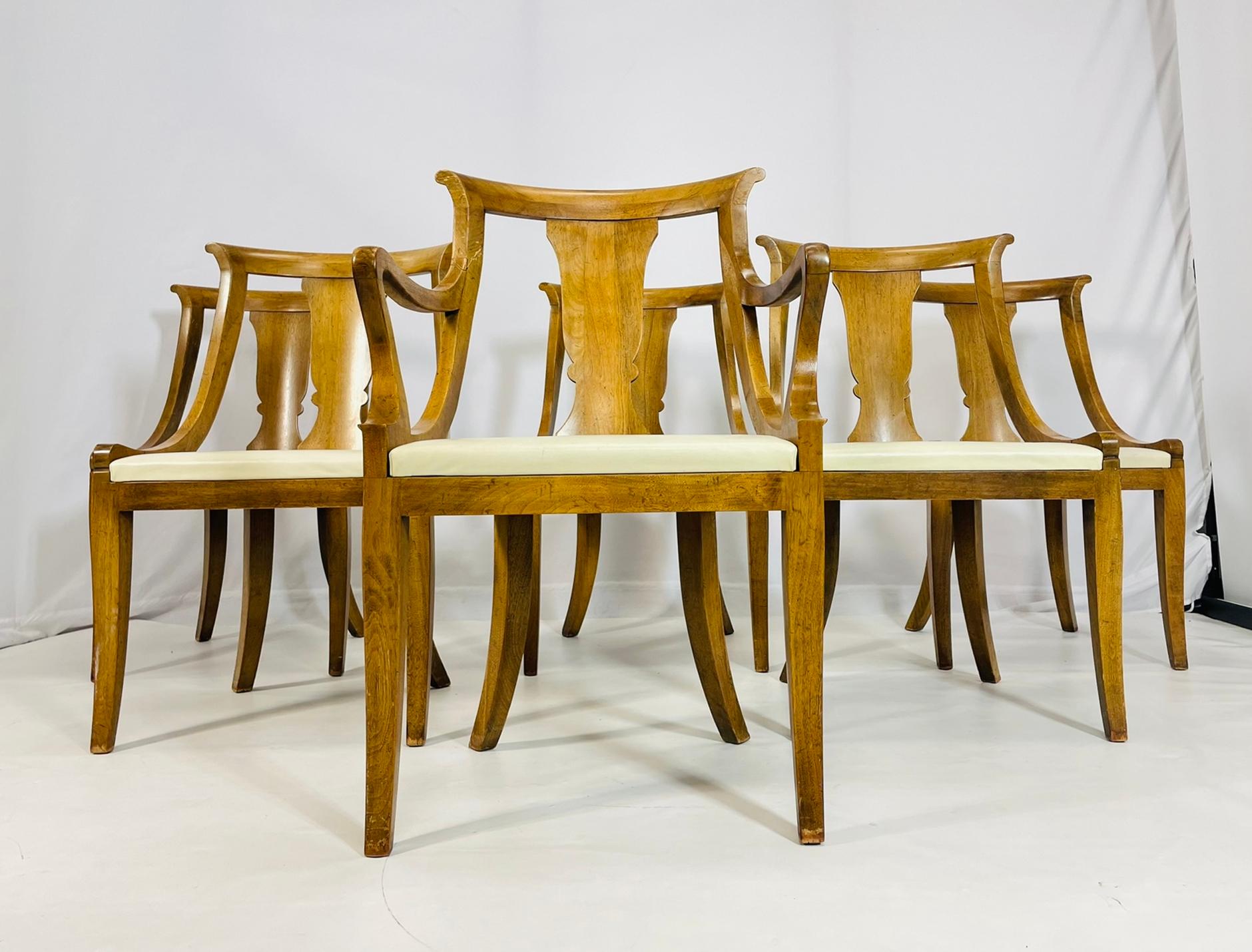 Elegante set di sei sedie da pranzo vintage con una classica silhouette in stile Klismos. Il set comprende cinque sedie laterali e una poltrona, tutte realizzate in legno ricco e dai toni caldi, con graziose gambe a sciabola e schienali curvi e