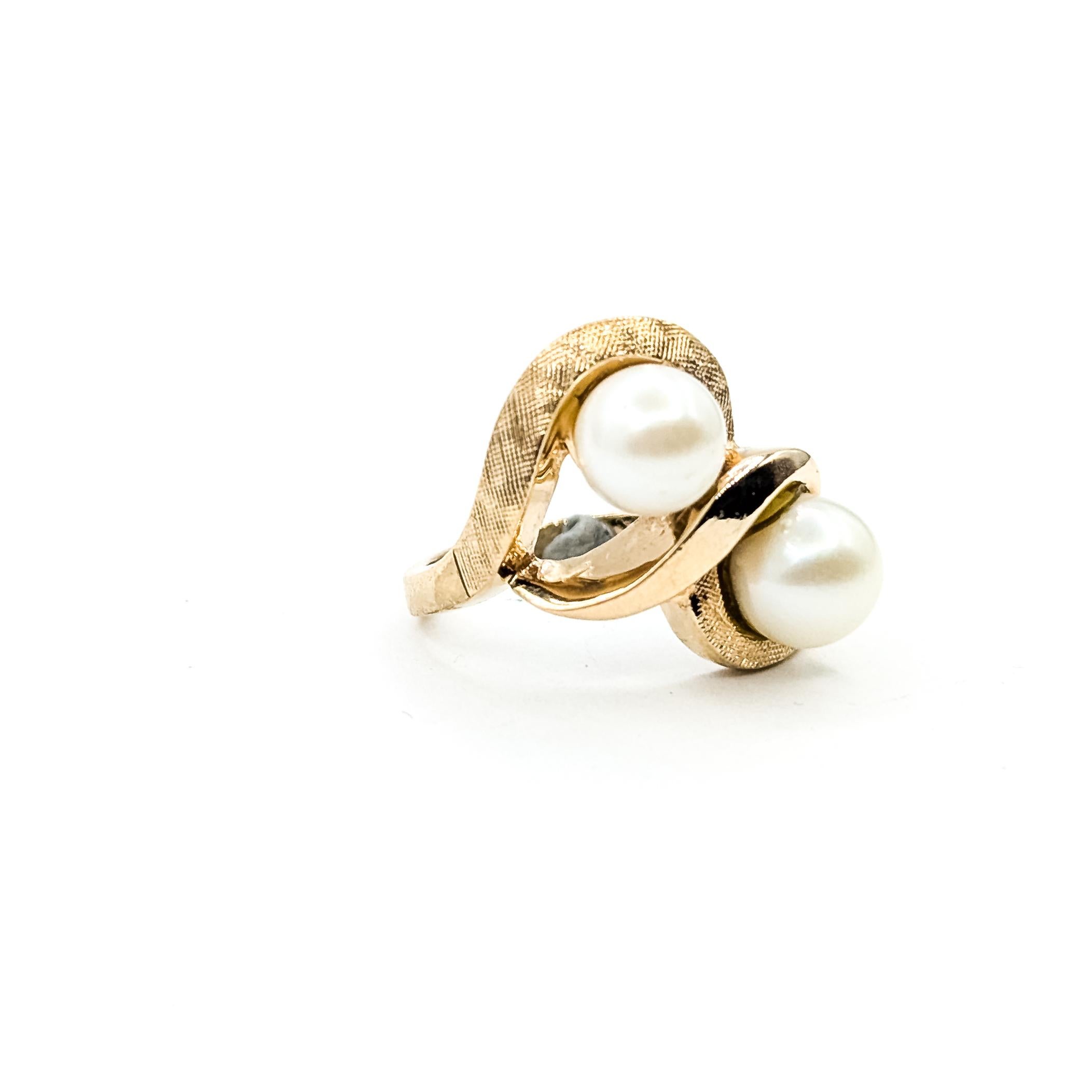 Vintage Knot Pearl Ring in 14k

This vintage ring is crafted in 14k yellow gold and features two round white pearls set within an elegant bypass-inspired swirl design. The textured gold details and fluid curves highlight the Mid-Century character of