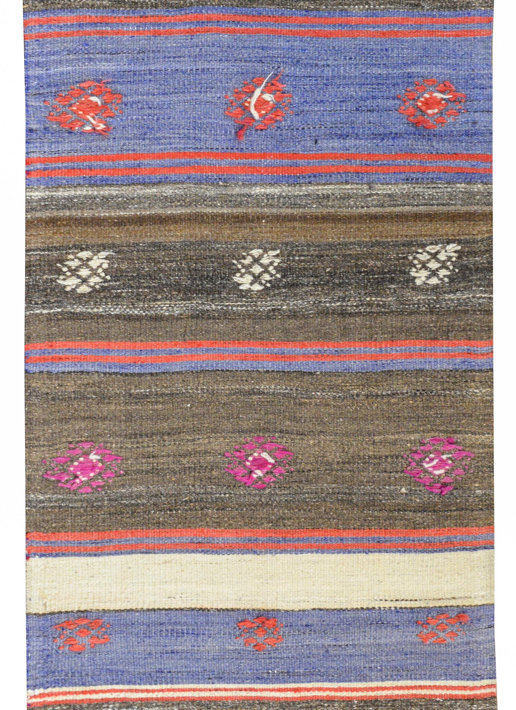 A wonderful vintage Turkish Konya Kilim runner with beautiful natural brown, black, cream, and gray stripes mixed with crimson and lavender vegetable dyed stripes, all with embroidered stylized flowers across the field.