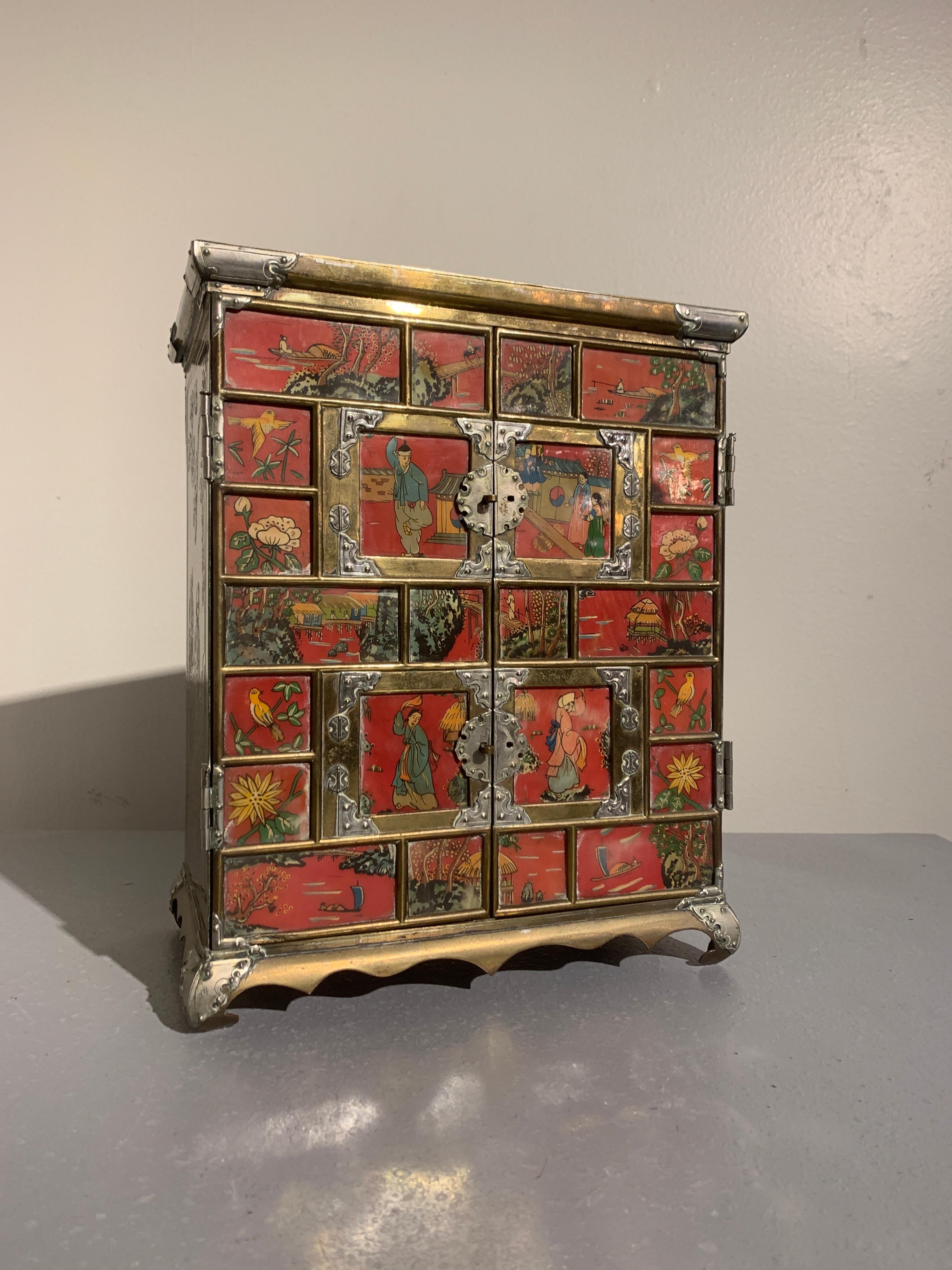 A wonderful vintage Korean brass jewelry cabinet with inset reverse painted ox horn panels, 1940s.

The jewelry chest, or possibly collectors cabinet, is in the shape of a traditional Korean clothing cabinet, with a brass frame and brass fittings.