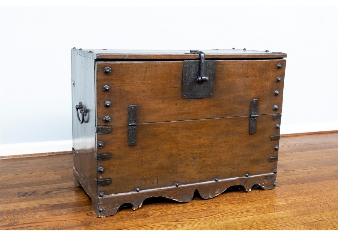 A quality Korean chest with a hinged drop front opening to storage. With black handwrought metal mounts with bosses and the lock. Carry handles on the sides. Raised on a serpentine skirt in front. 
Measures: wide 30 1/2