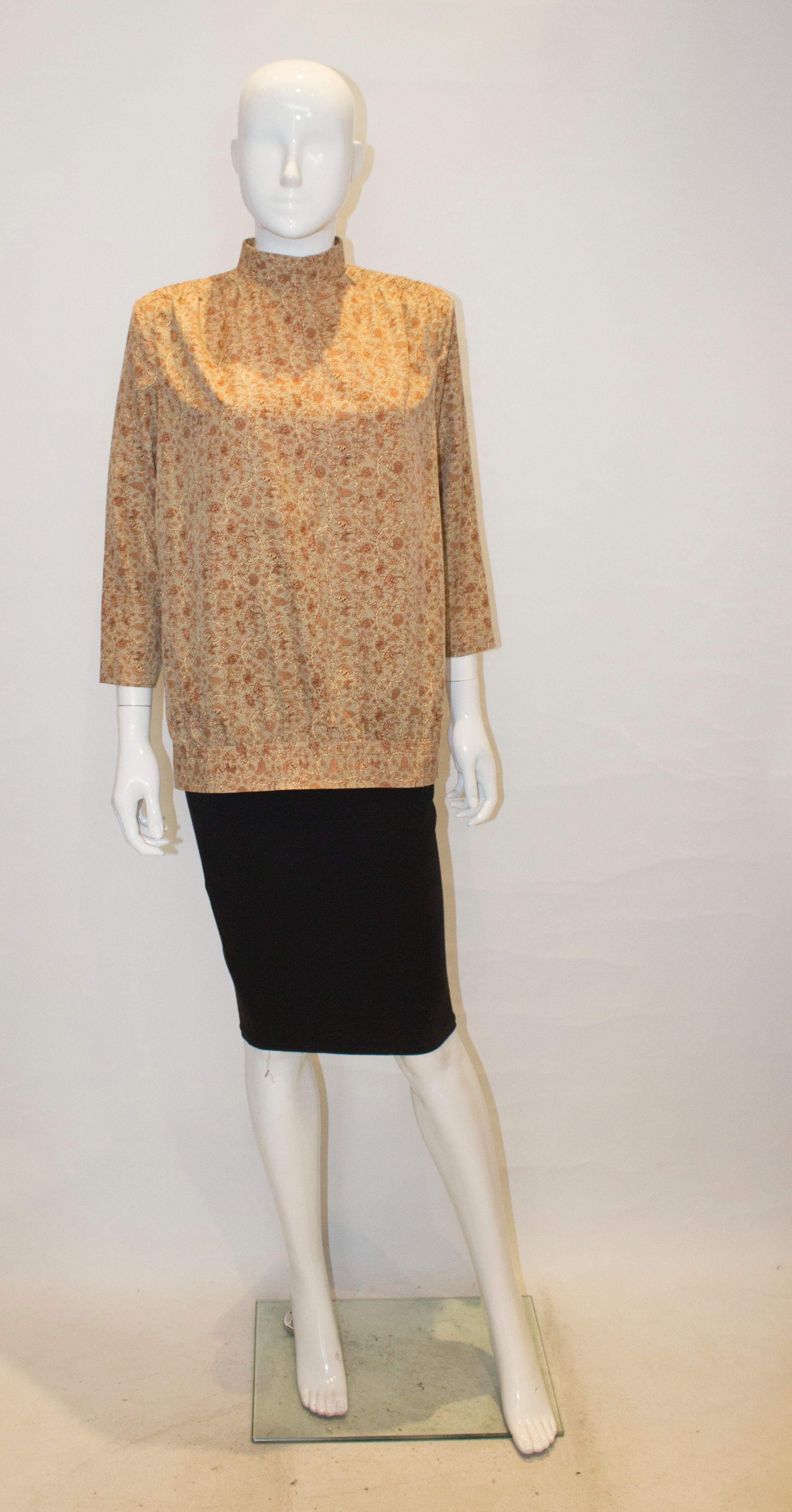 A pretty vintage kossak style blouse, in a brown floral fabric. The top has smoking detail on the shoulders , and a hook and eye fastening at the back.