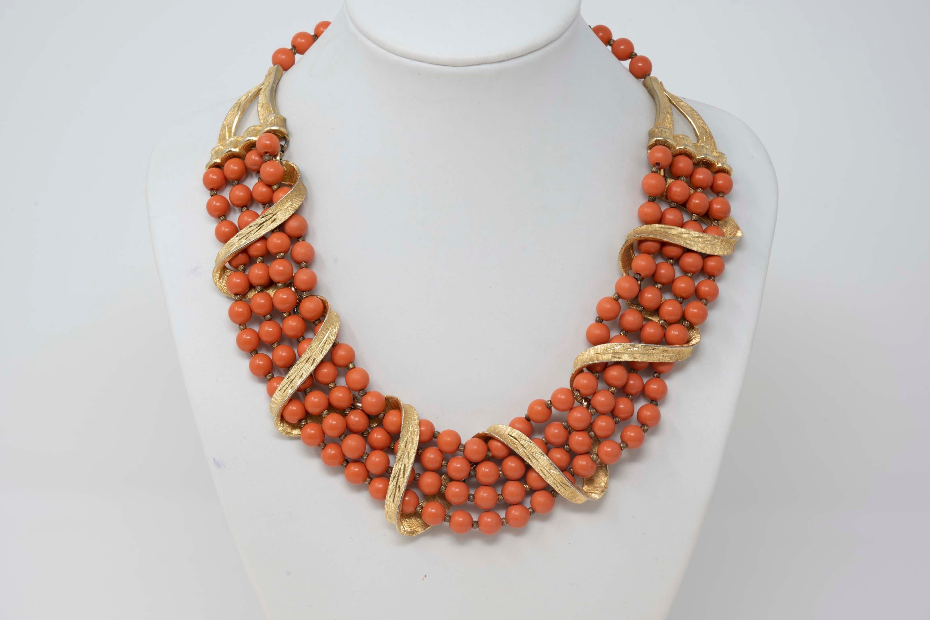 Vintage Kramer multistrand necklace with gilt metal and coral color beads. Stamped on the back, 17 1/2 inches long x 1 1/4 inches wide. Made in the USA, circa 1950-1960. In good condition.
