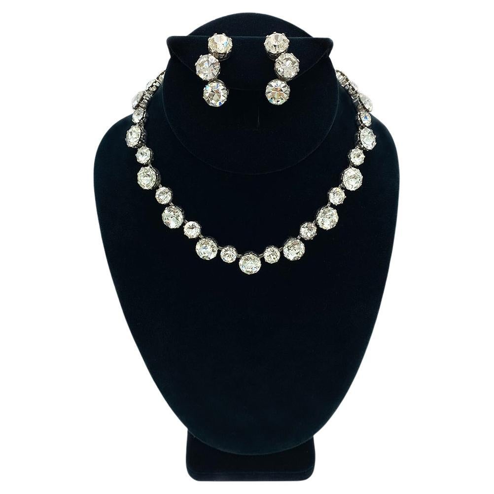 This is a Kramer NY necklace & earrings set. The Hollywood Regency style necklace is linked with 8 & 11 mm sparkling round rhinestones on rhodium-plated backings. The clip-on earrings are set with three 11 mm rhinestones in a crescent shape. This