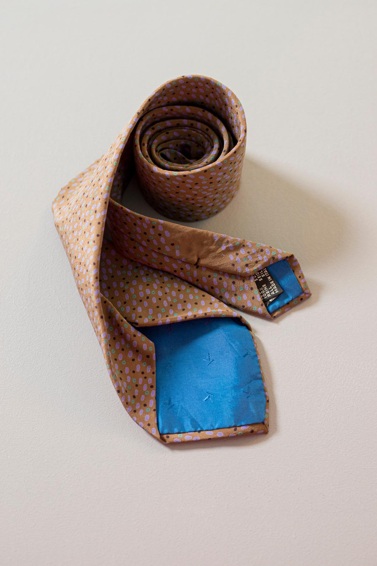 Elegant vintage tie designed by Krizia, it is made of silk. Decorated with small dots of three colors: green, lilac and black, on a light brown background. If your goal is to have a simple but at the same time never dull look, this is the perfect