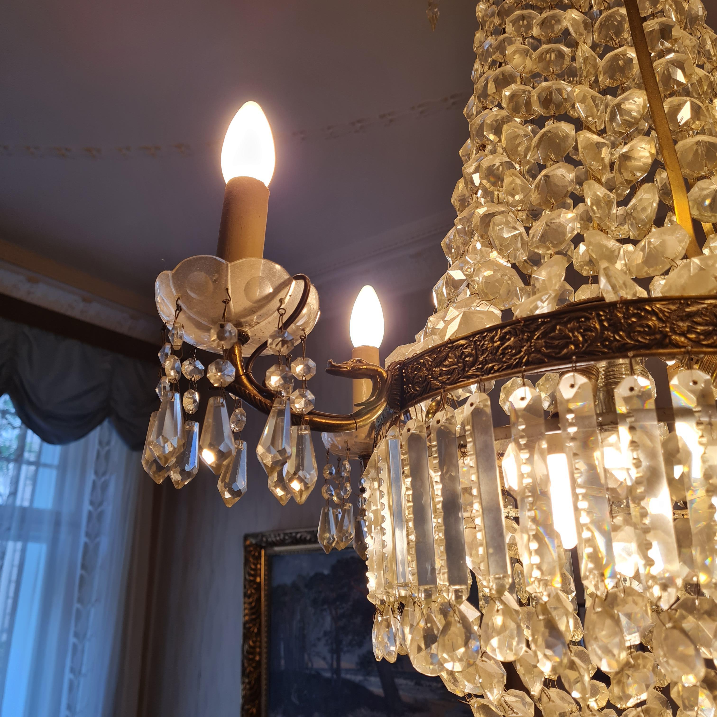 Empire style crystal chandelier decorated with rich ornamental brass patterns. The chandelier has 4 well chiseled brass arms that support the candles, 8 lights (4 external and 4 internal E14/ E27). Elegant and very bright chandelier has the shape of