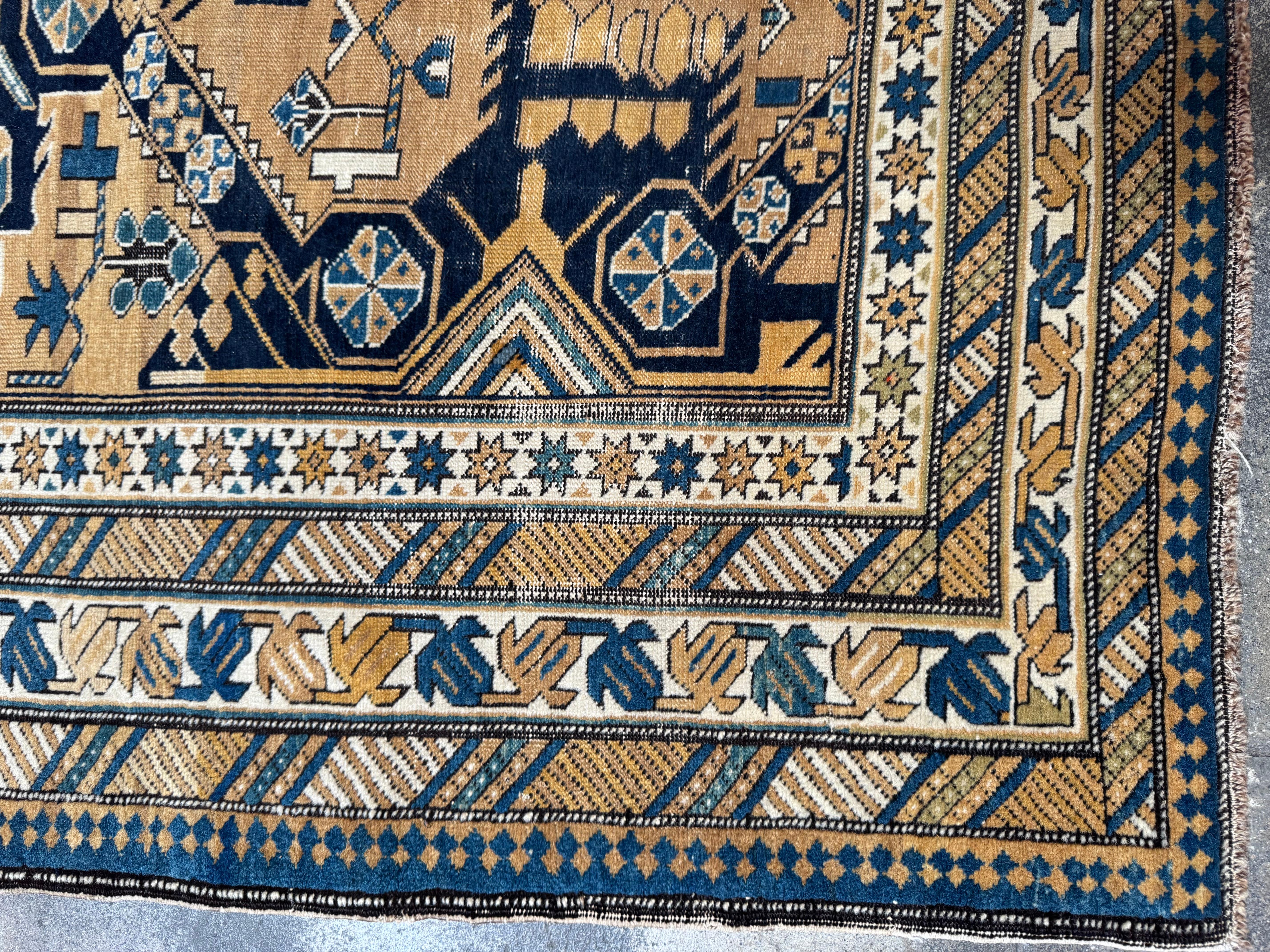 Ce tapis Kuba Cseikhong vintage est une pièce frappante de l'artisanat caucasien, présentant une disposition complexe de médaillons en croix tribaux et de motifs géométriques stylisés. Sur un fond chaud de couleur camel, les motifs symétriques en