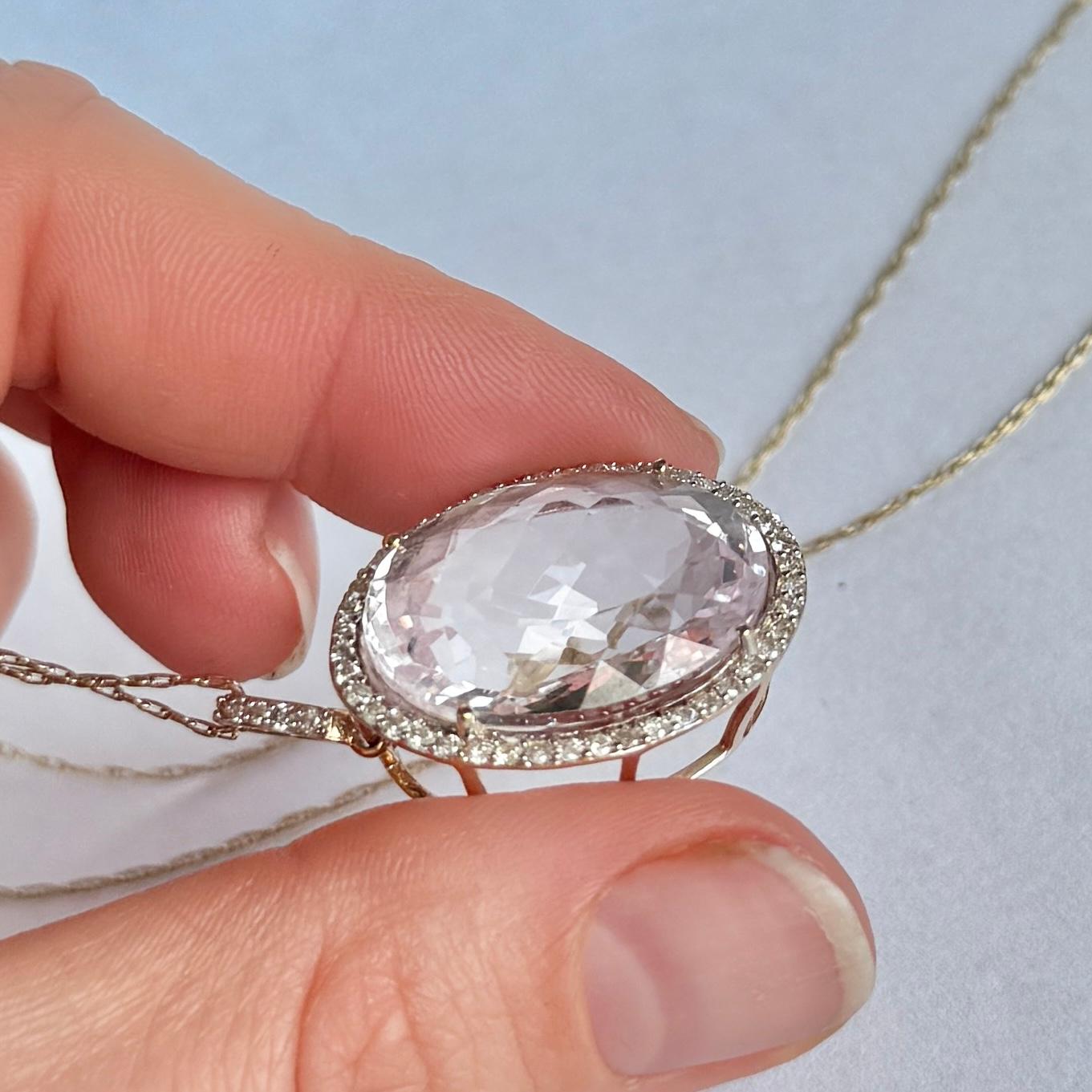 Dieser schöne Anhänger aus 9-karätigem Gold trägt einen großen Kunzit-Stein in der Mitte und ist von einem Kranz aus Diamanten mit einem Gesamtgewicht von 90 Pence umgeben. Der Anhänger ist an einer Kette aus 9 Karat Gold befestigt.

Kunzit