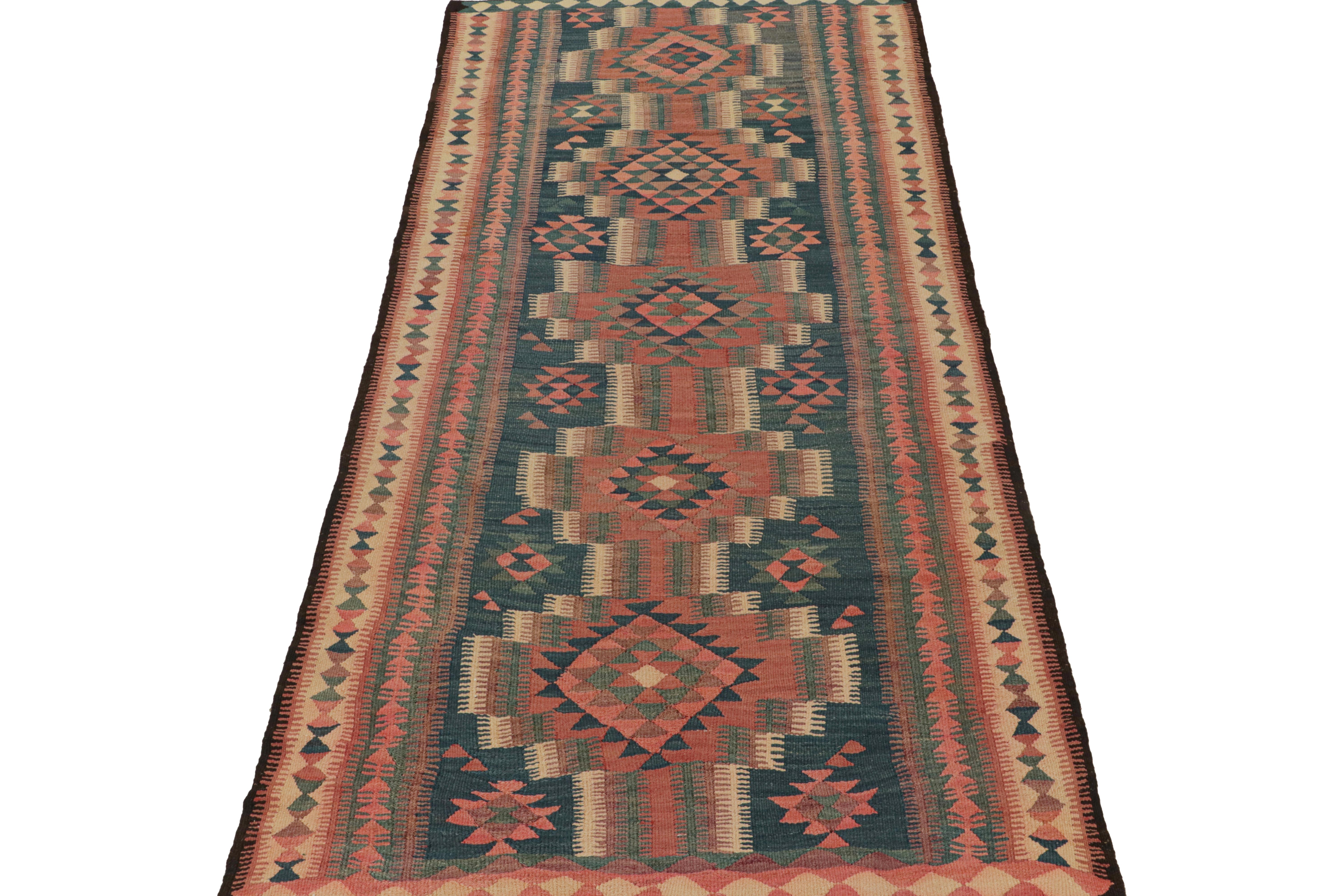 This vintage 5x10 Persian Kilim is believed to be a Kurdish tribal runner of the 1950s. 

Handwoven in wool, its design enjoys geometric patterns in brick red and navy blue with teal and beige accents. It’s an exemplary work of Persian Folk Art
