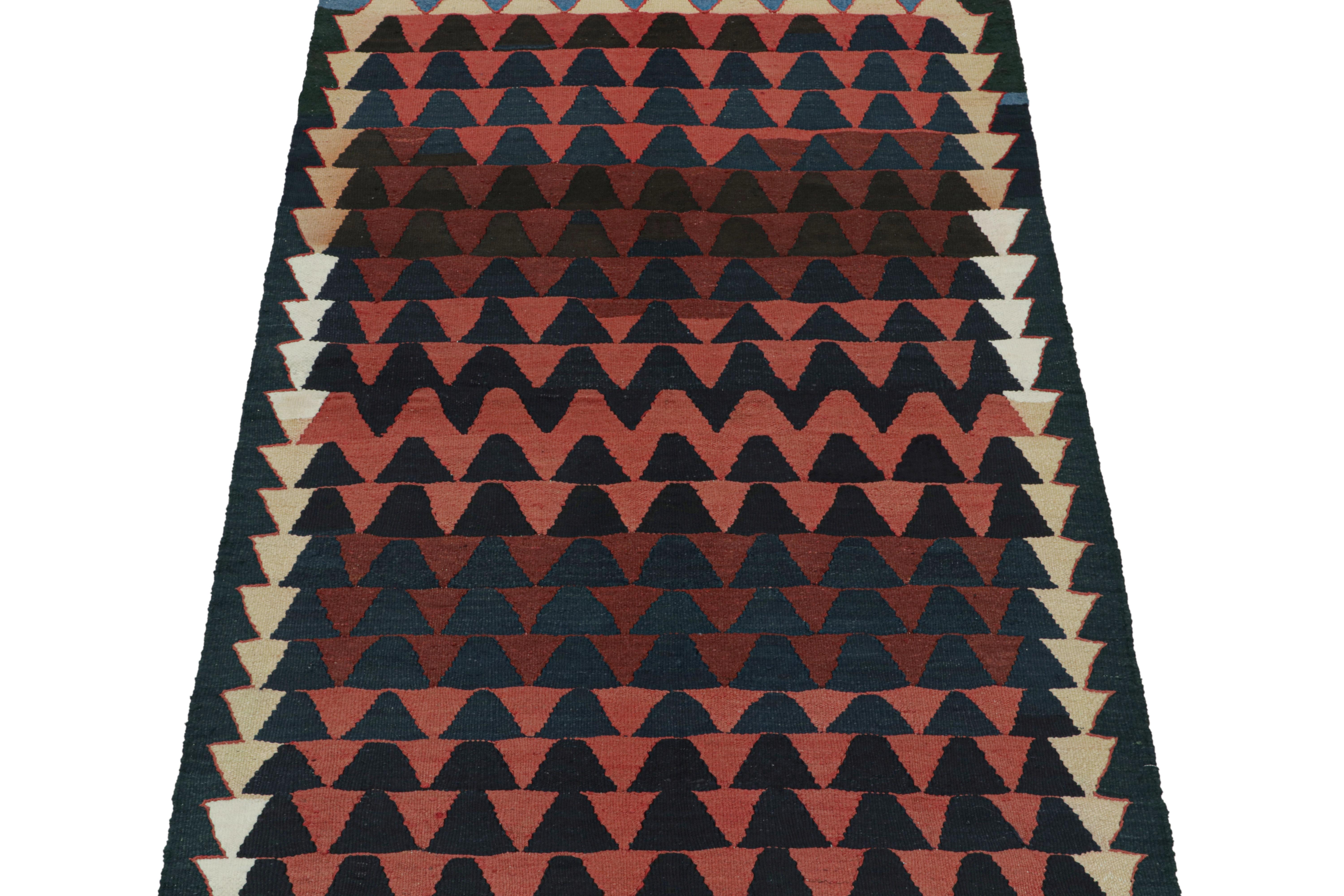 This vintage 5x8 Persian Kilim is believed to be a midcentury tribal rug from Kurdistan.

Handwoven in wool circa 1950-1960, its design favors an all-over geometric pattern in repeat rows with navy blue and red. Keen eyes will further note