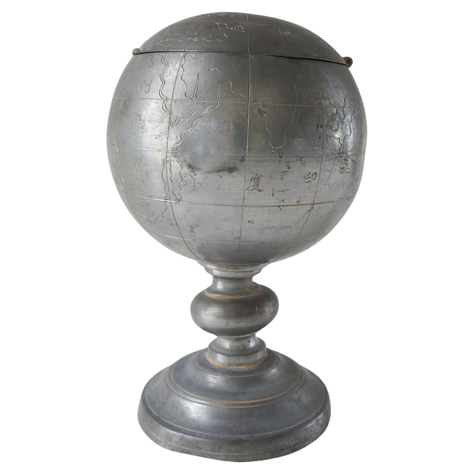 Vintage circa 1920's pewter tea caddy or cigarette box in the shape of a world globe on stand. Made in China and marked Kut Hing Swatow.  Globe opens to interior insert with lid, overall patina, few small dings.