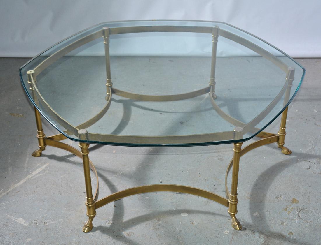 A brass hexagonal coffee table with hoof feet and glass top attributed to La Barge. Original condition with natural patina on base and some surface scratching to glass top.