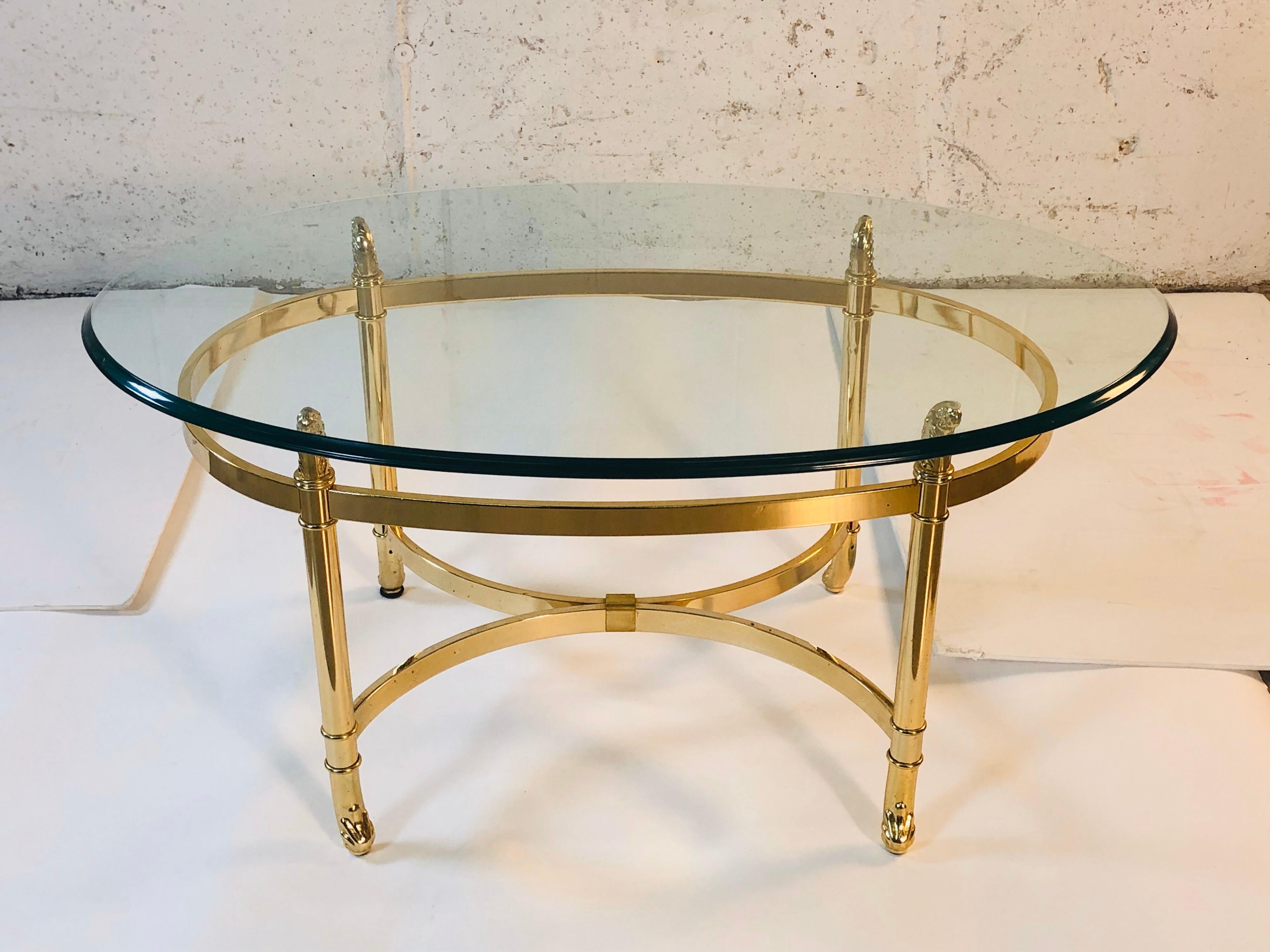 Vintage 1960s small LaBarge style oval brass base and glass top coffee table. The table has scroll accents on the feet and holding the glass. The glass top has a nice deep bevel. Light tarnish and pitting from age. Glass has a couple of light