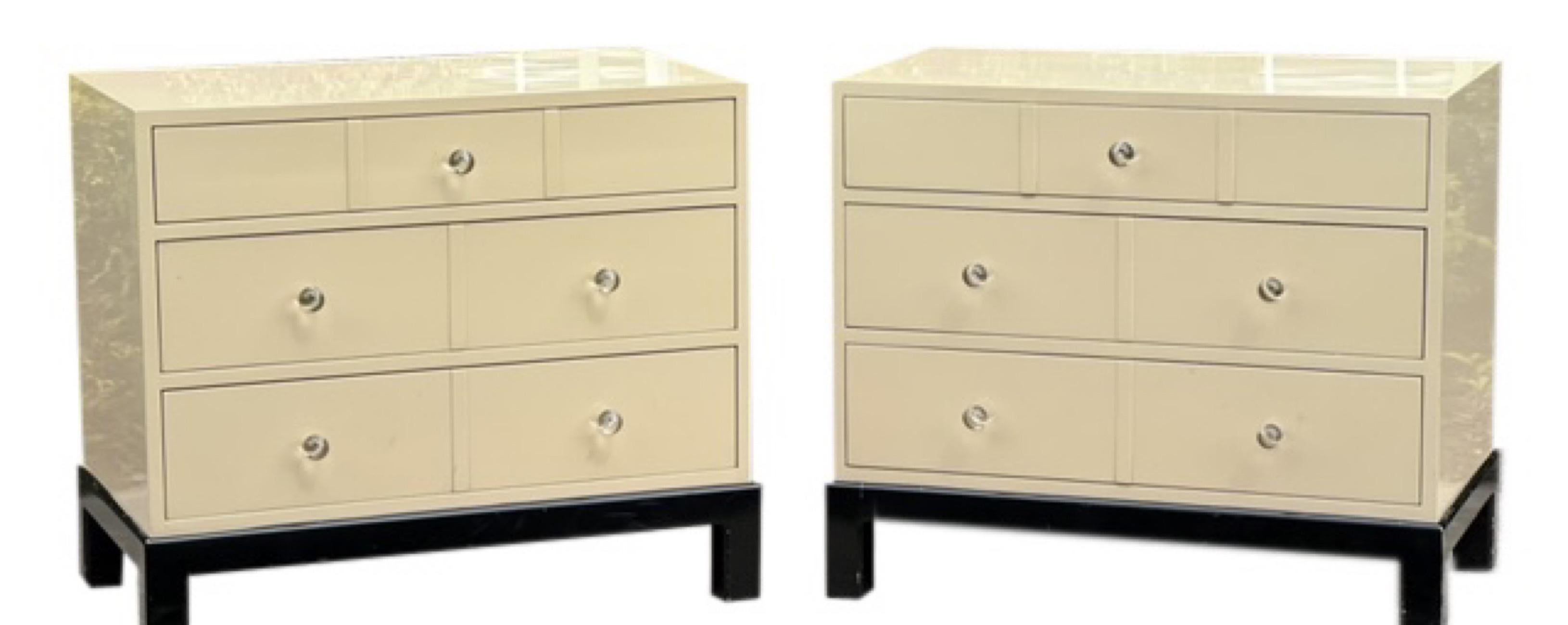Beautiful pair of 1970's three drawer nightstands or chests with lucite knobs. The finish is a glossy pale taupe lacquer with black bases and finished backs. The pair is well crafted and in very good condition showing little signs of use. Modern and
