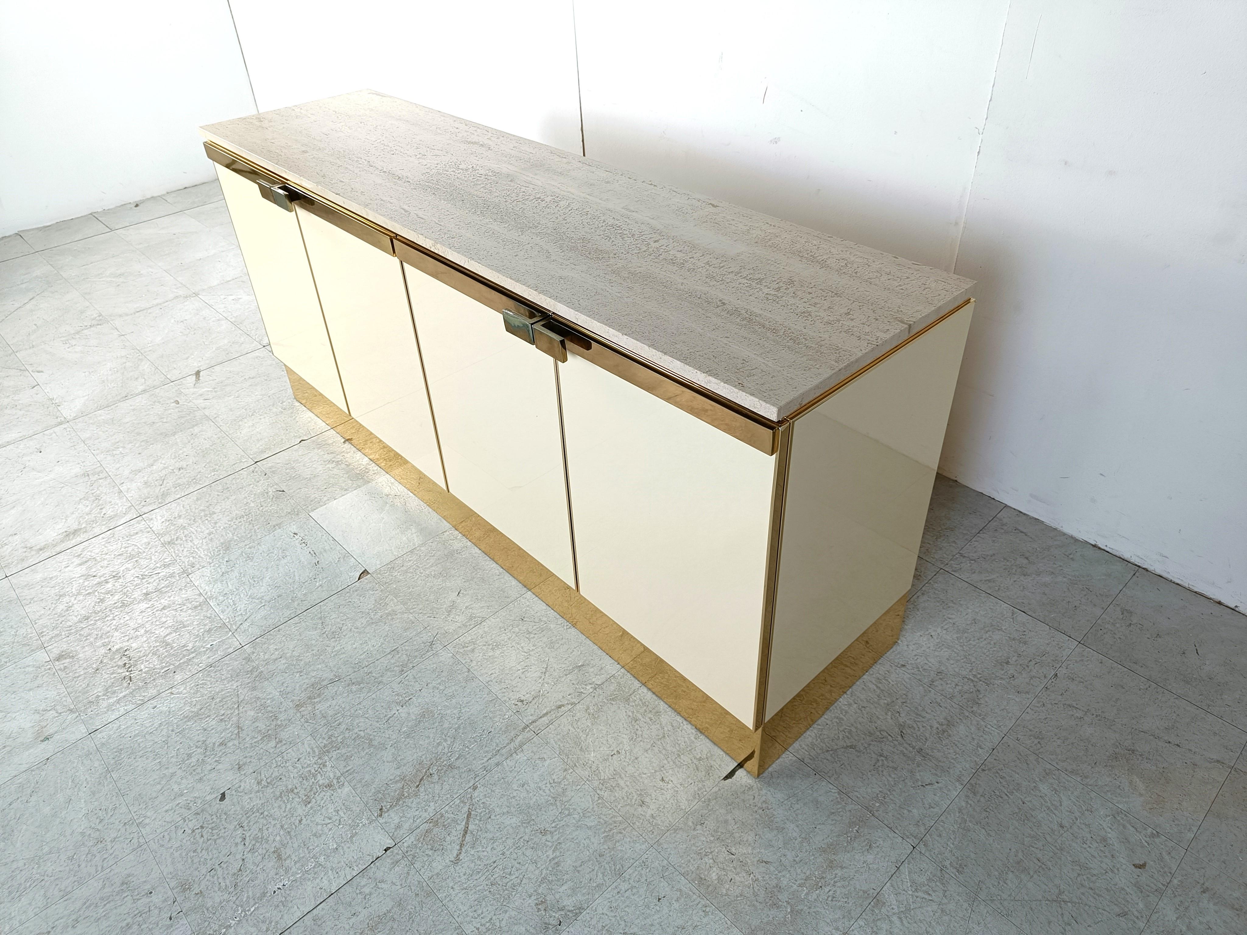 Beautiful beige lacquered credenza with 4 doors and brass hardware.

The sideboard is finished with a nice travertine table top 

Good condition.

1980s - France

Dimensions:
Lenght: 180cm
Height: 80cm
Depth: 50cm

Ref.: 213421