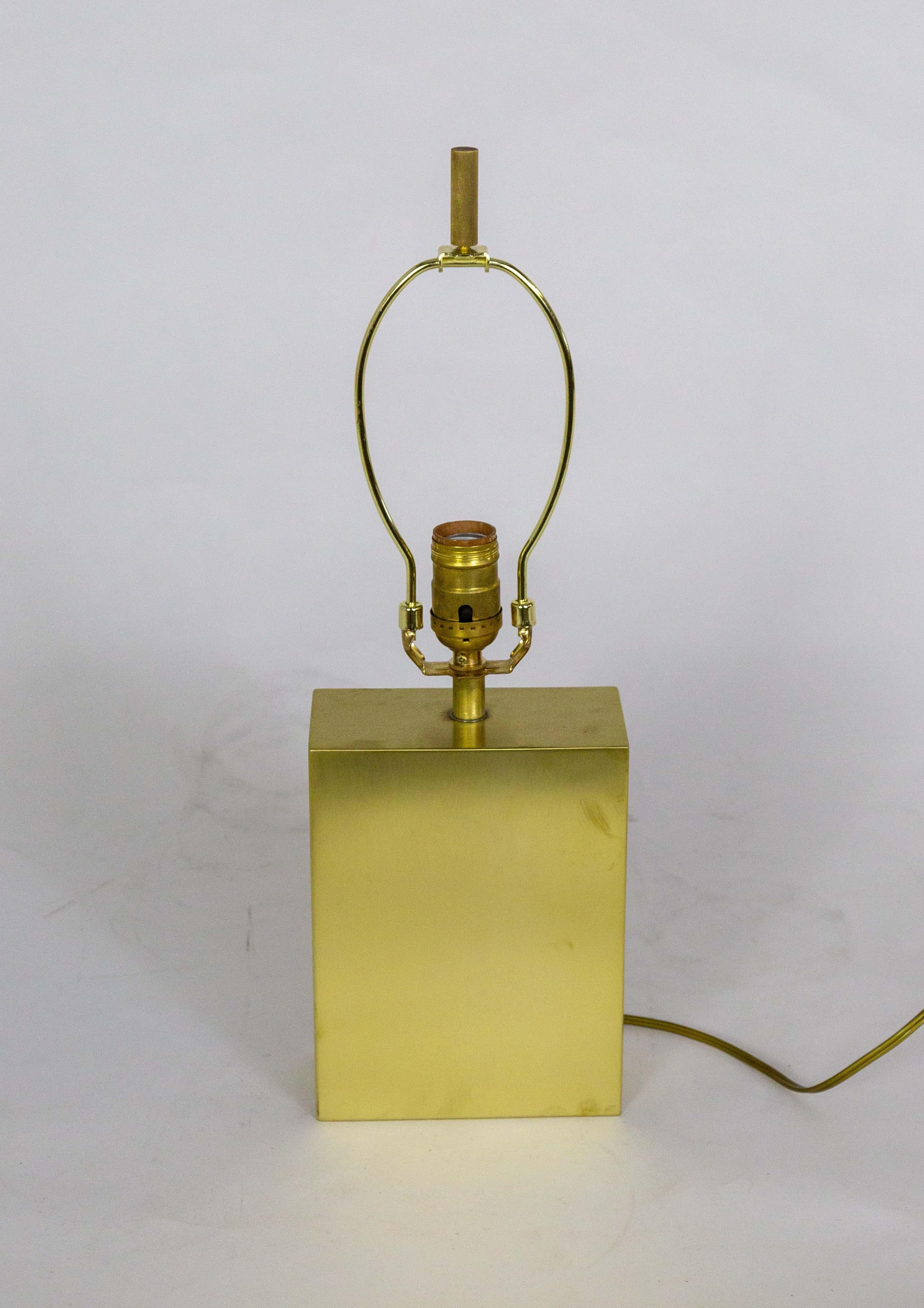A small, versatile, vintage table lamp with a clean, slick look. It is a rectangular shape made of raw brass, with a 