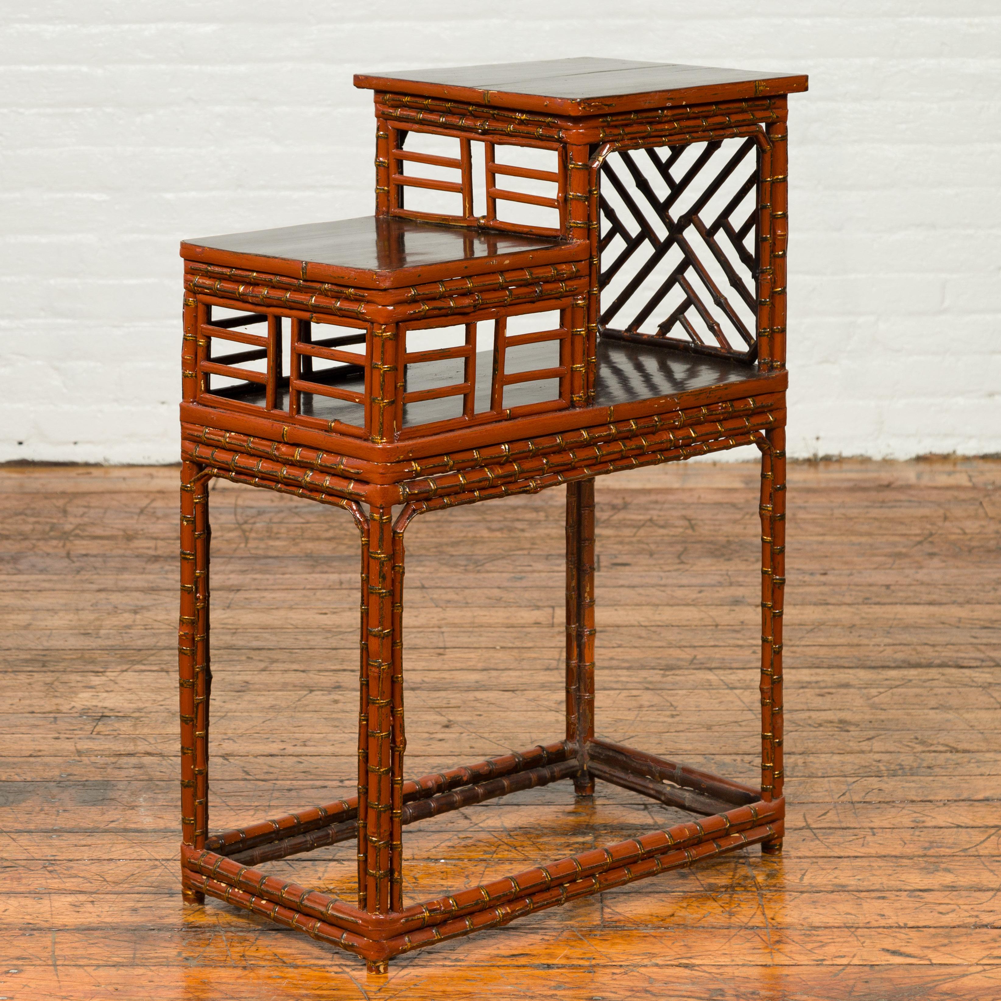 A Chinese vintage tiered bamboo lamp table from the mid-20th century, with geometric patterns. Born in China during the midcentury period, this handsome lamp table features a tiered silhouette accented with geometric patterns and dark lacquered