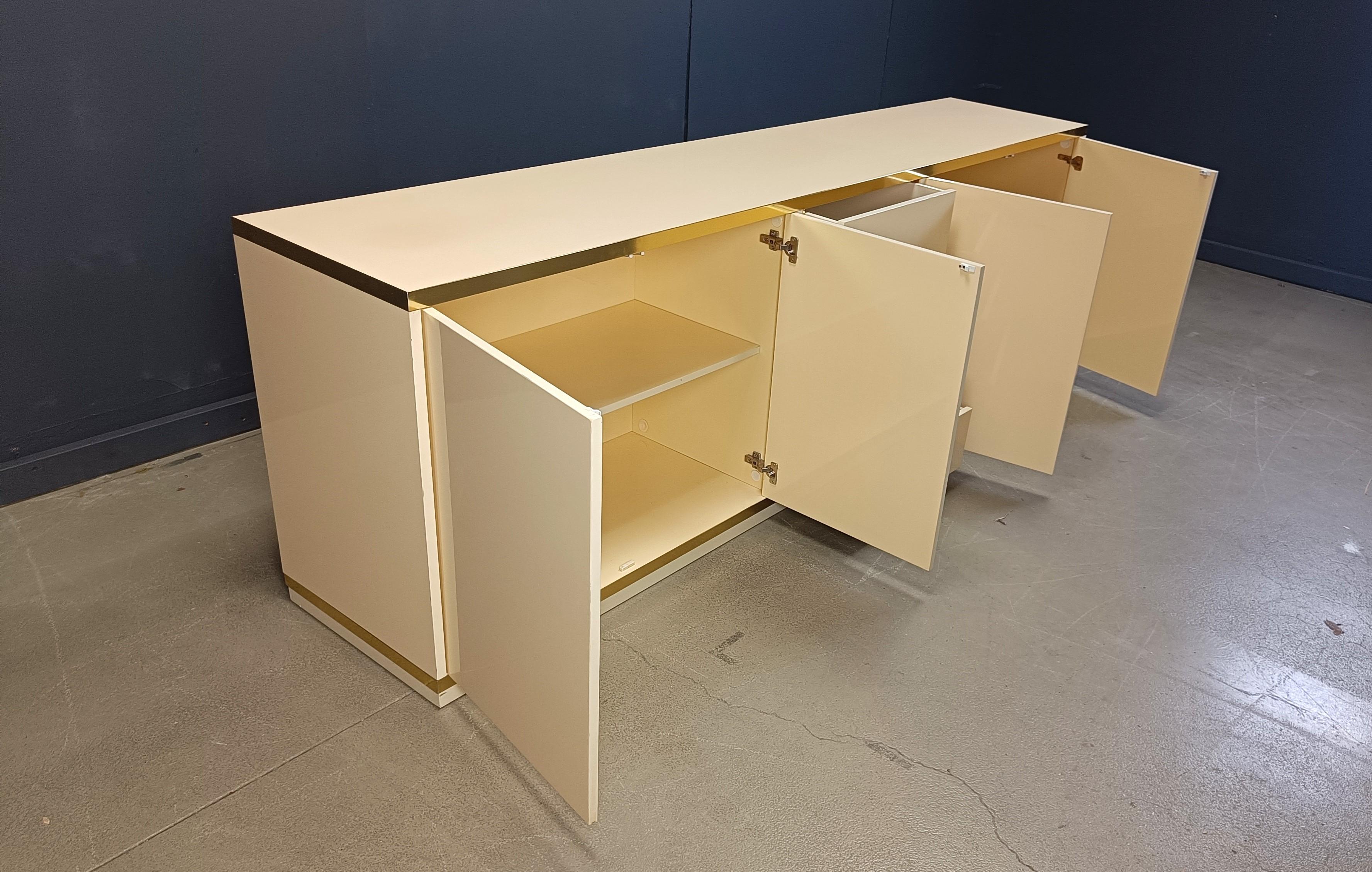 Vintage french beige lacquered wooden credenza with brass hardware consisting of 4 doors and 4 drawers.

High quality finish with a finished backpanel so It can serve as a room divider.

Good condition

1980s - France

Dimensions:
Height: