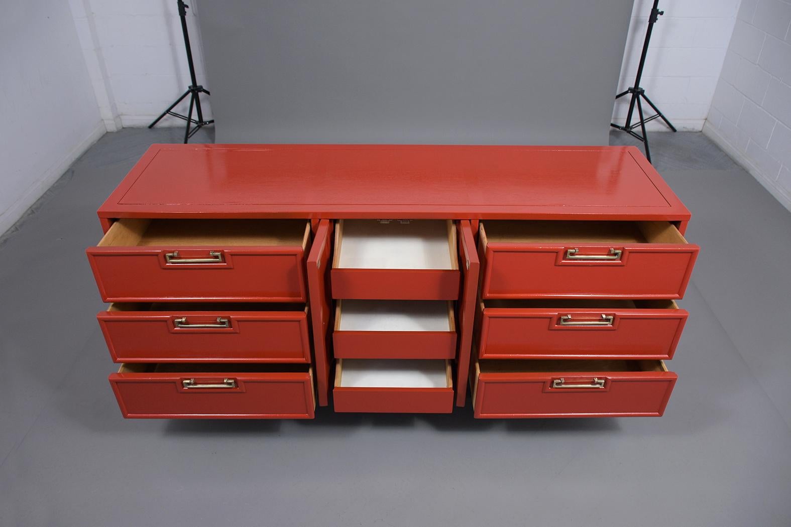 An extraordinary 1960's mid-century modern credenza made out of maple wood, is newly stained in a red & ebonized color combination with lacquer finish and has been professionally restored. This chest of drawers is eye-catching features six drawers,