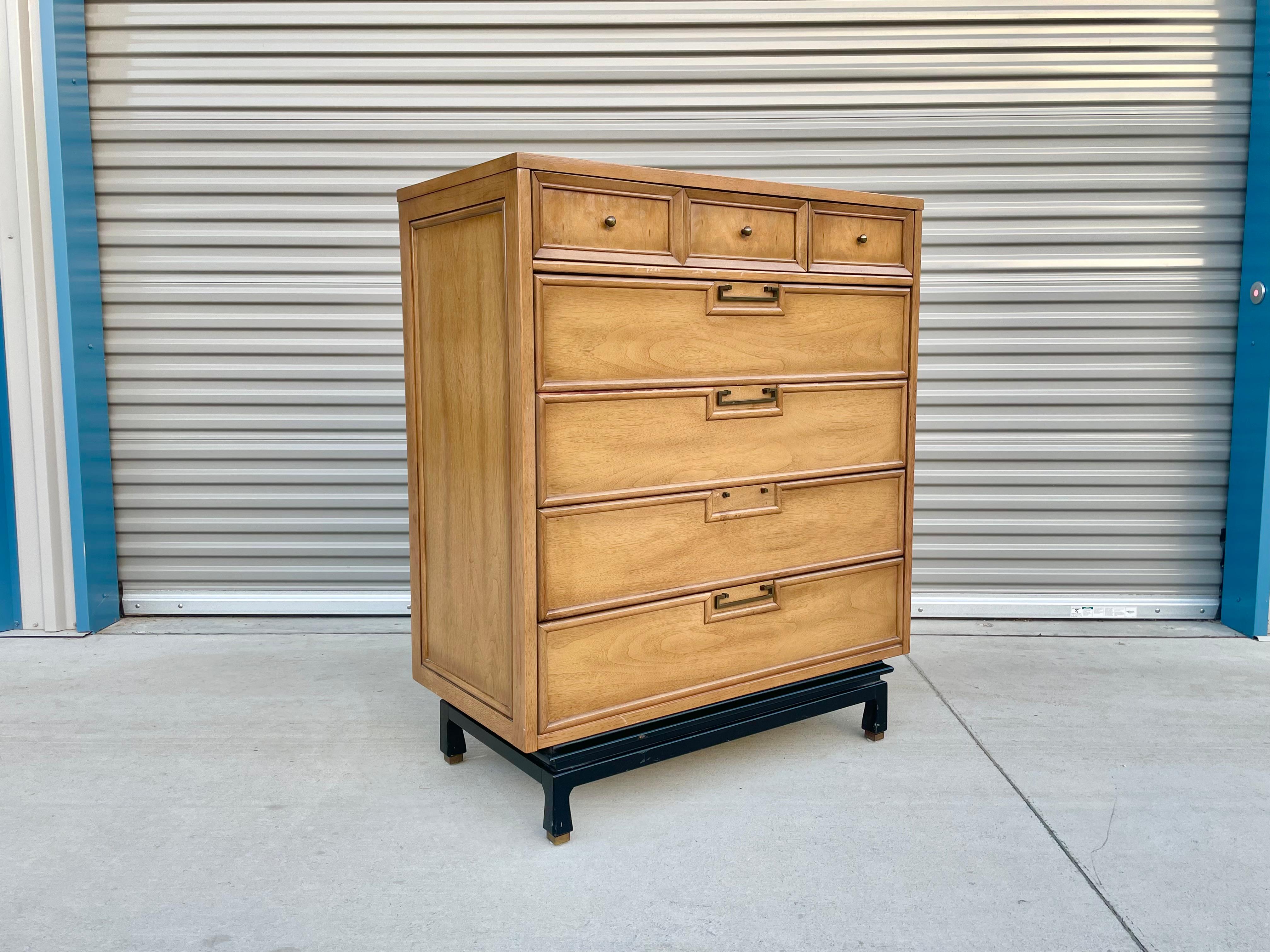 This stunning vintage highboy was designed and manufactured by American of Martinsville in the United States, circa 1950s. This elegant highboy features seven drawers with original brass handles and sits on a sculpted black base with brass sabots.