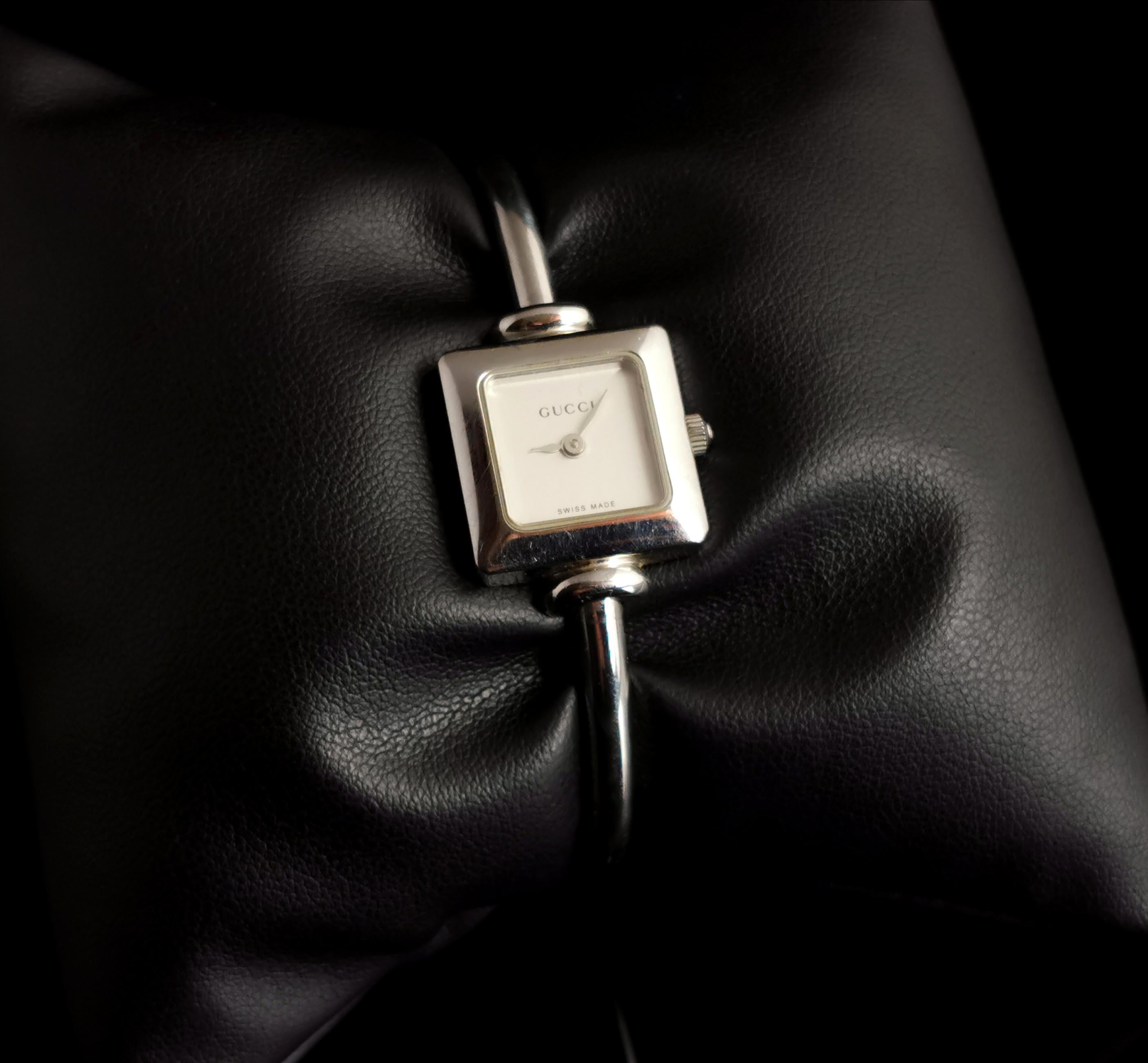 Eine wunderschöne Vintage Gucci 1900 L Damenarmbanduhr in der originalen Box mit Papierkram.

Diese stilvolle Uhr hat ein Edelstahlarmband und ein quadratisches Zifferblatt, das Zifferblatt ist weiß, ohne Ziffern und mit einem schwarzen Gucci-Logo