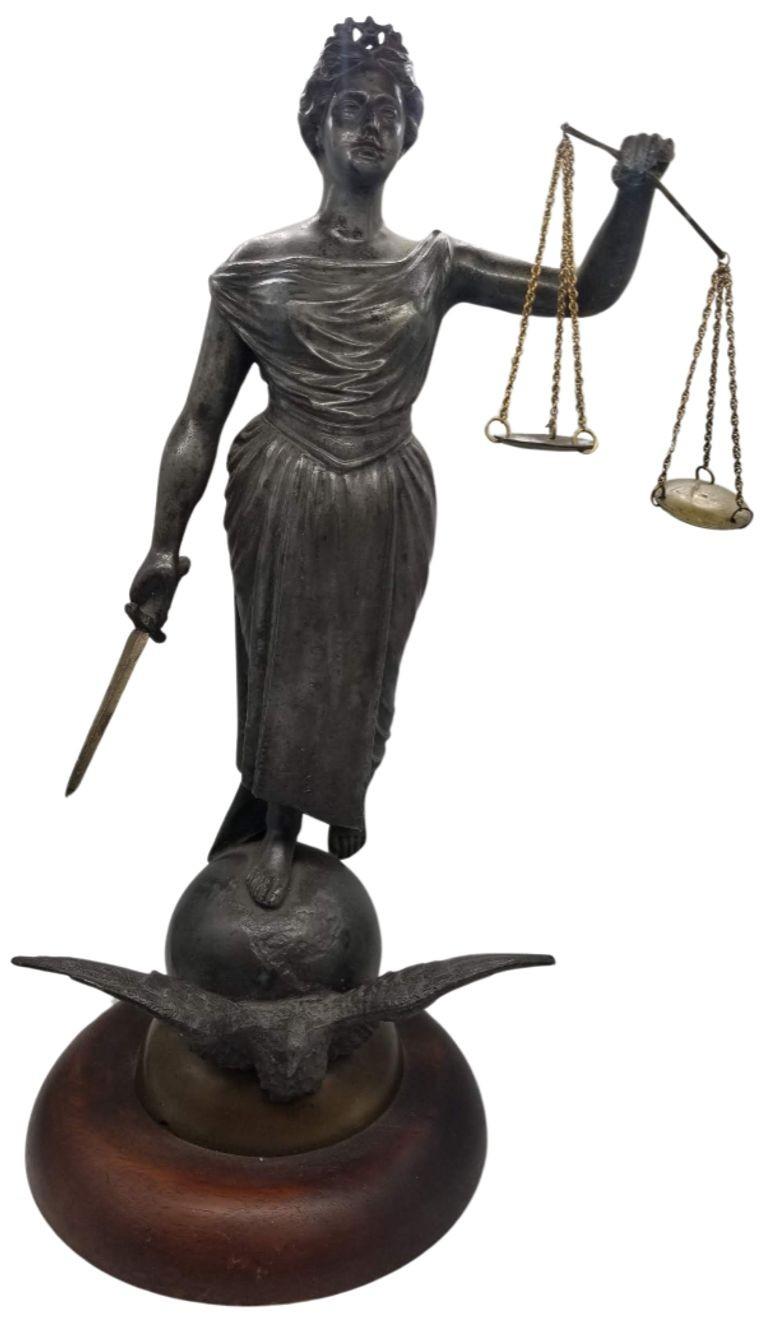 Vintage Lady Justice Resolute is a captivating sculpture that deviates from the traditional representation of Lady Justice by omitting the blindfold, revealing a resolute and unwavering gaze. Crafted with meticulous detail and a nod to classical