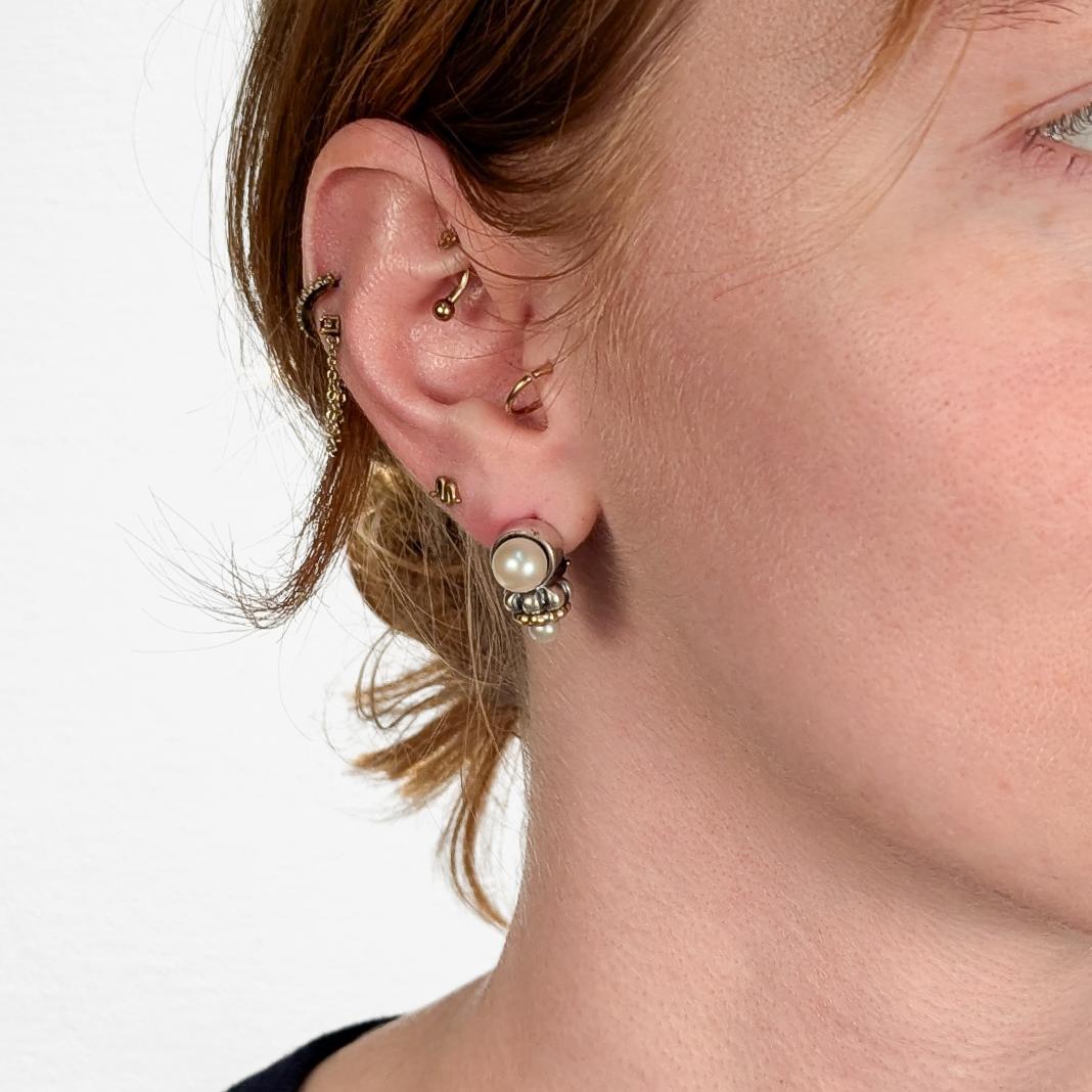 A fine pair of vintage signed earrings.

By Lagos.

In sterling silver with 18 karat yellow gold accents.

From the Caviar collection.

Each bezel-set with a pearl, and with a smaller pearl as a reverse finial.

With omega clip closures.

Fully